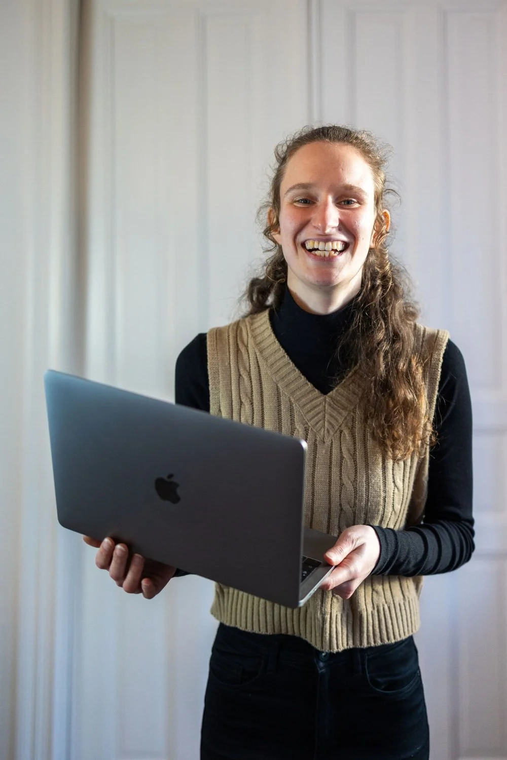 Webdesignerin lacht mit Laptop in Händen