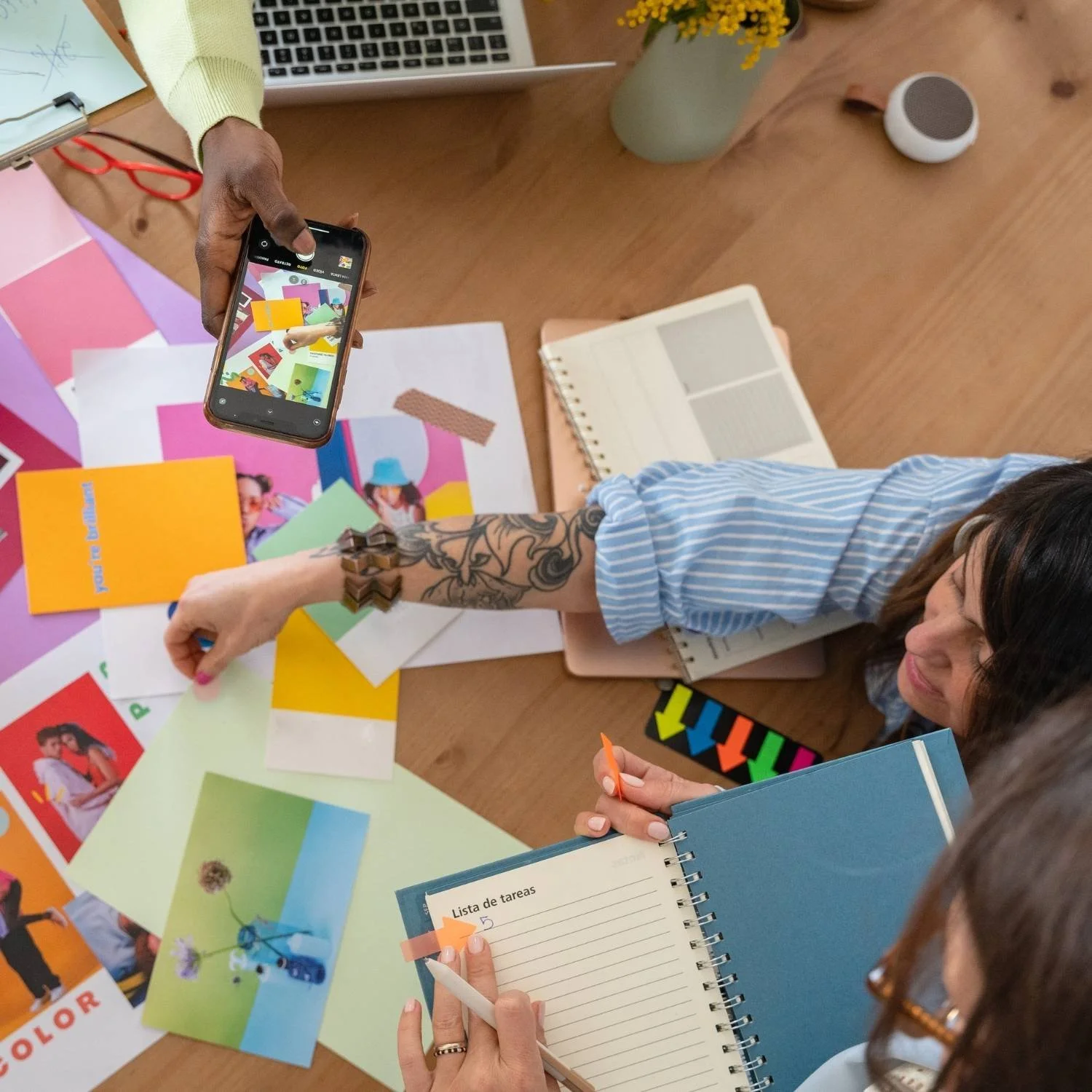3 Selbstständige führen mit buntem Papier und Fotos auf Tisch Website Redesign durch