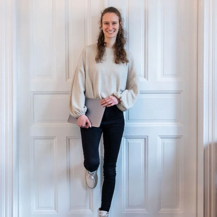 Maike mit Laptop vor weißer Altbautür