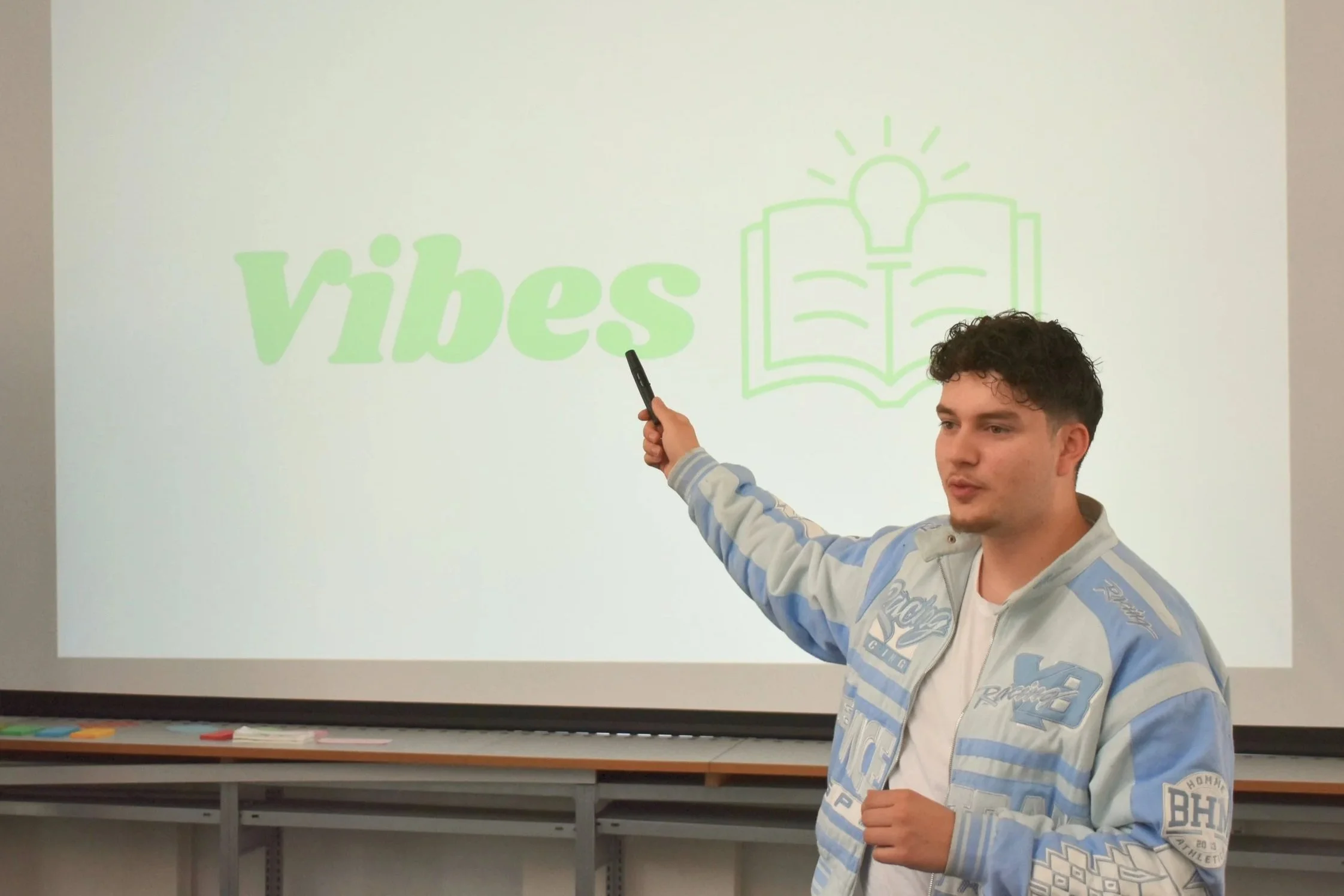Serdar hält Präsentation und zeigt auf Vibes Logo