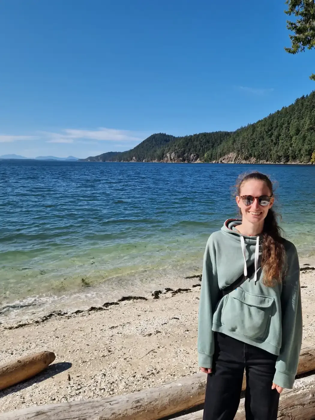 Maike steht lächeln vor Strand und Meer in Kanada