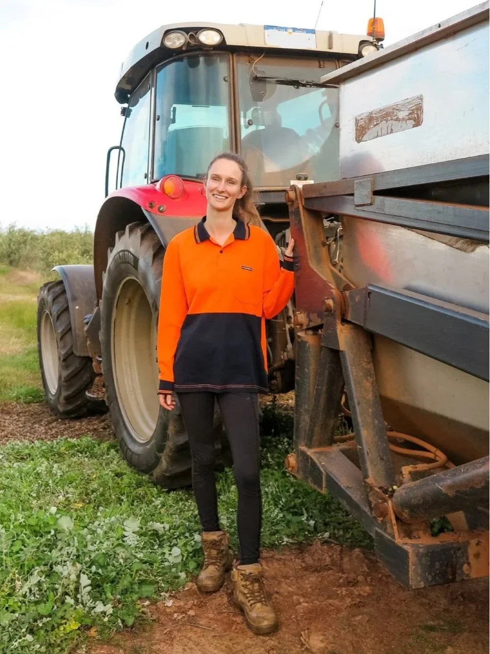 Maike steht in Arbeitskleidung vor Traktor in Australien
