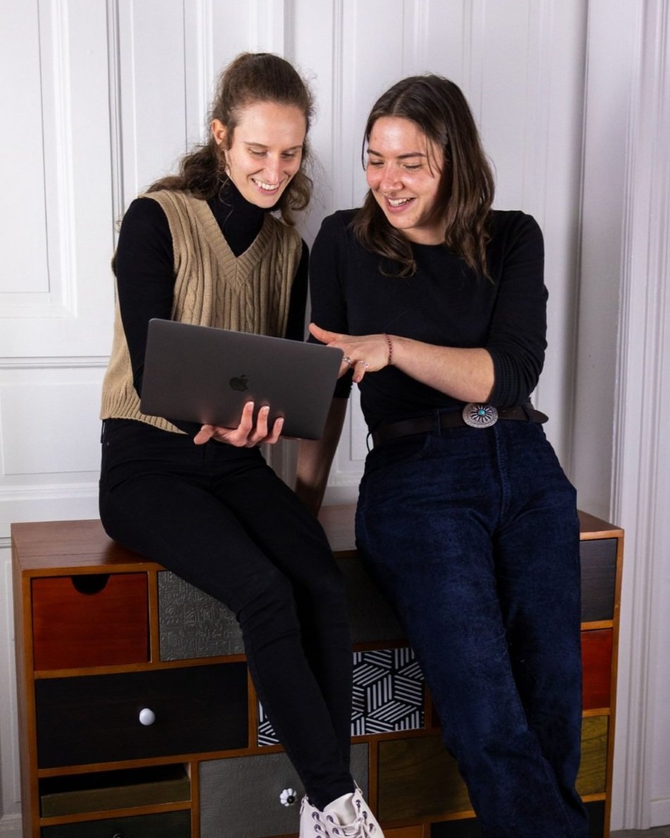 Zwei Webdesignerinnen unterhalten sich über Website auf Laptop