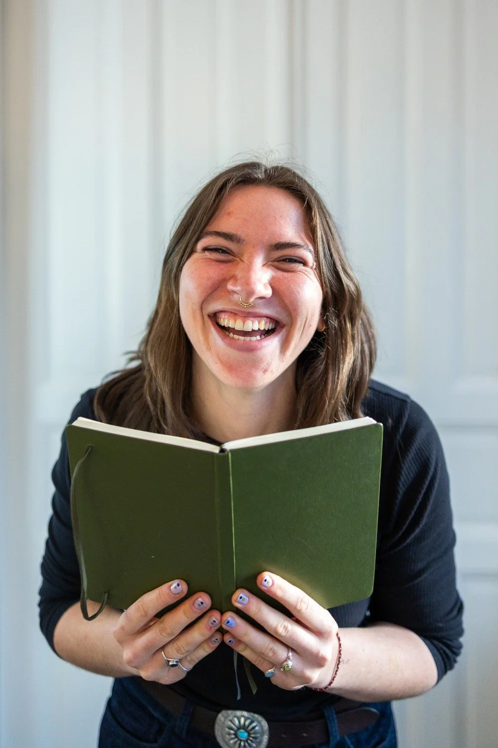 Webdesignerin lacht mit Bullet Journal in Händen