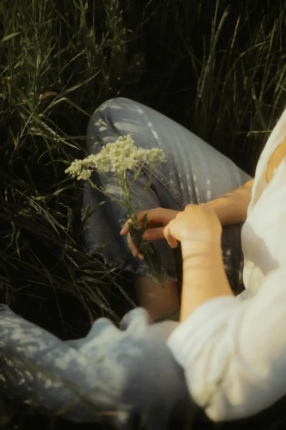 Frau sitzt mit Blume auf Wiese