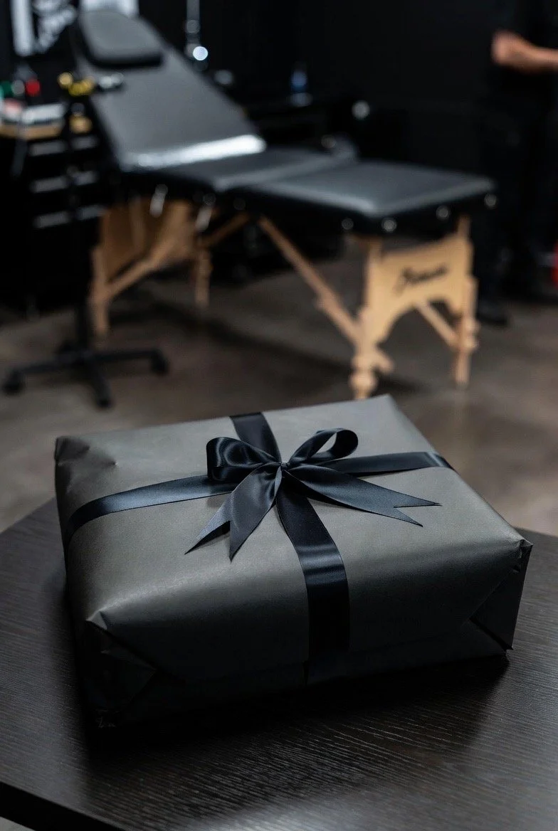 Un cadeau enveloppé en papier noir avec un ruban noir, posé sur une table en bois.