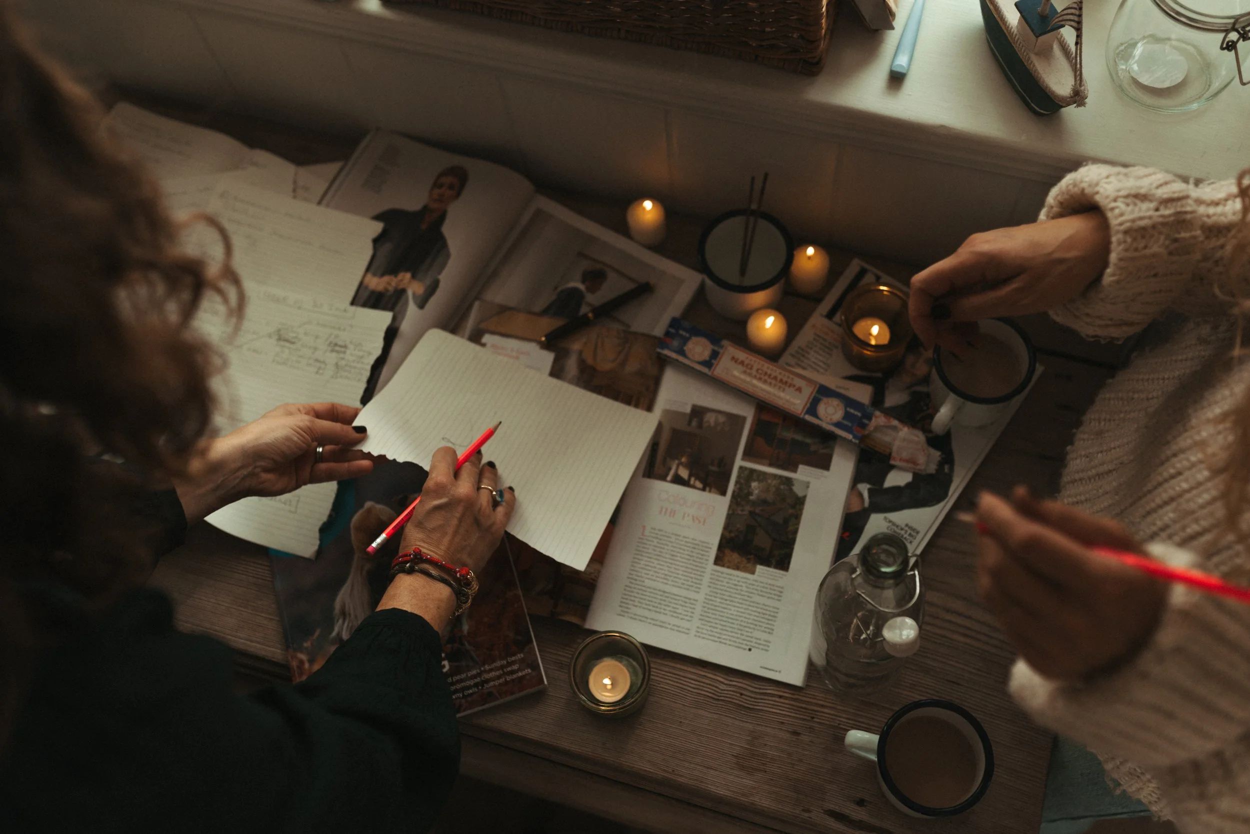 Two women founders (Manfreda and Felicity of Salt & Sage Storytelling) discussing a content strategy for a lifestyle brand in a candle-lit, coastal-inspired office.