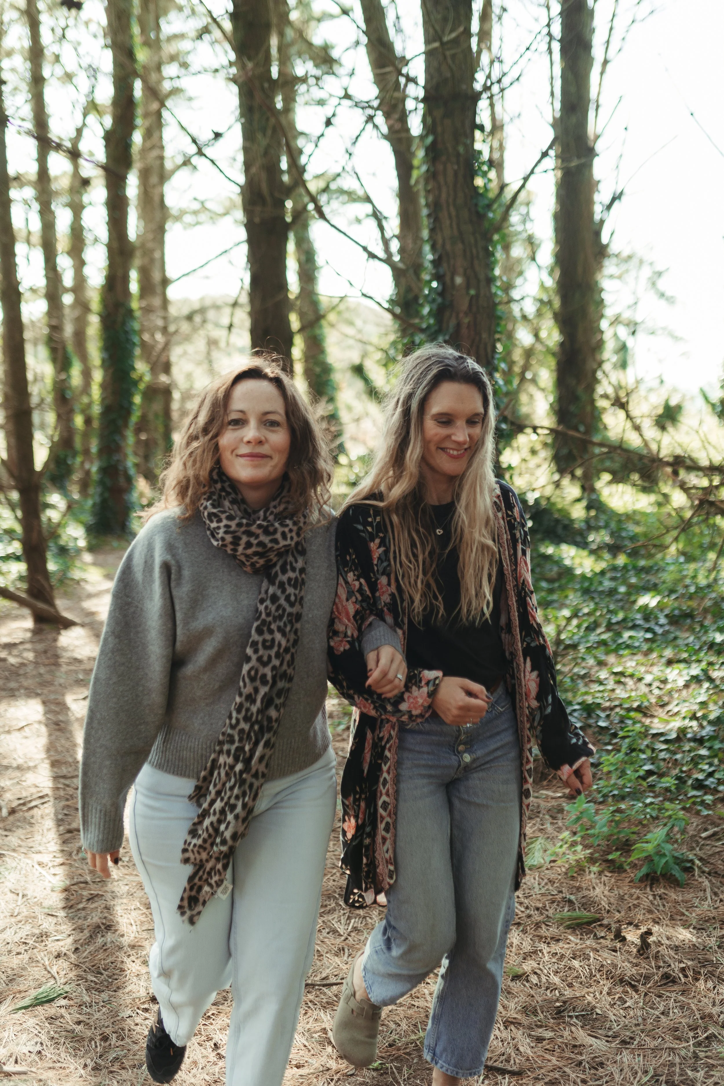 Two women sitting at a table having a discussion, with notebooks, a laptop, and coffee mugs.