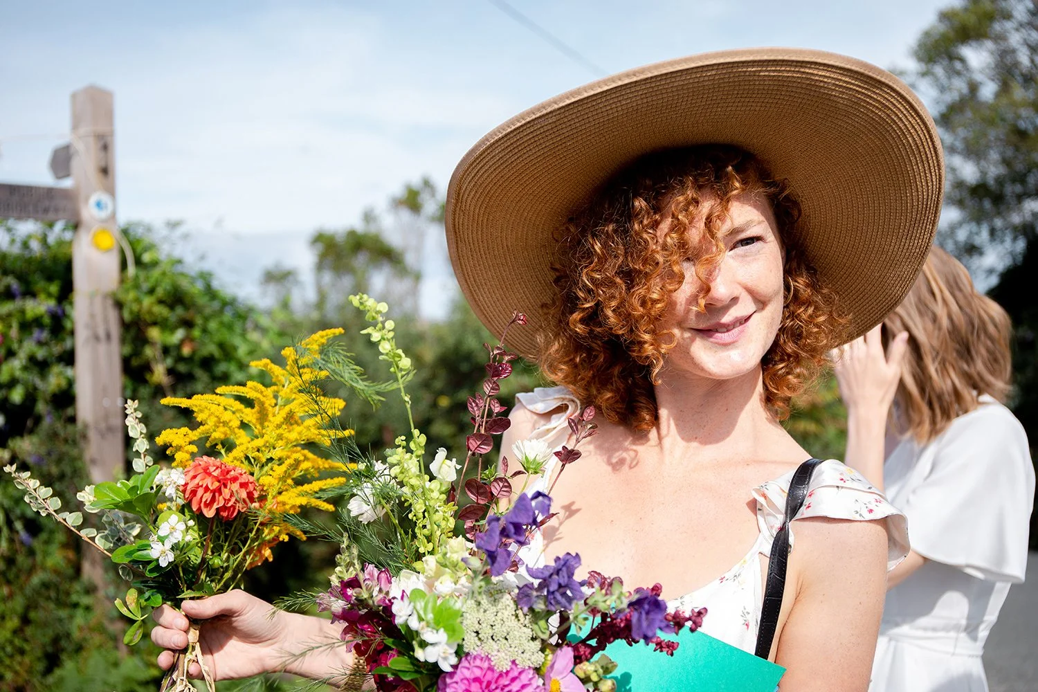 beautiful bridesmaid with flowers and summer hat smiling