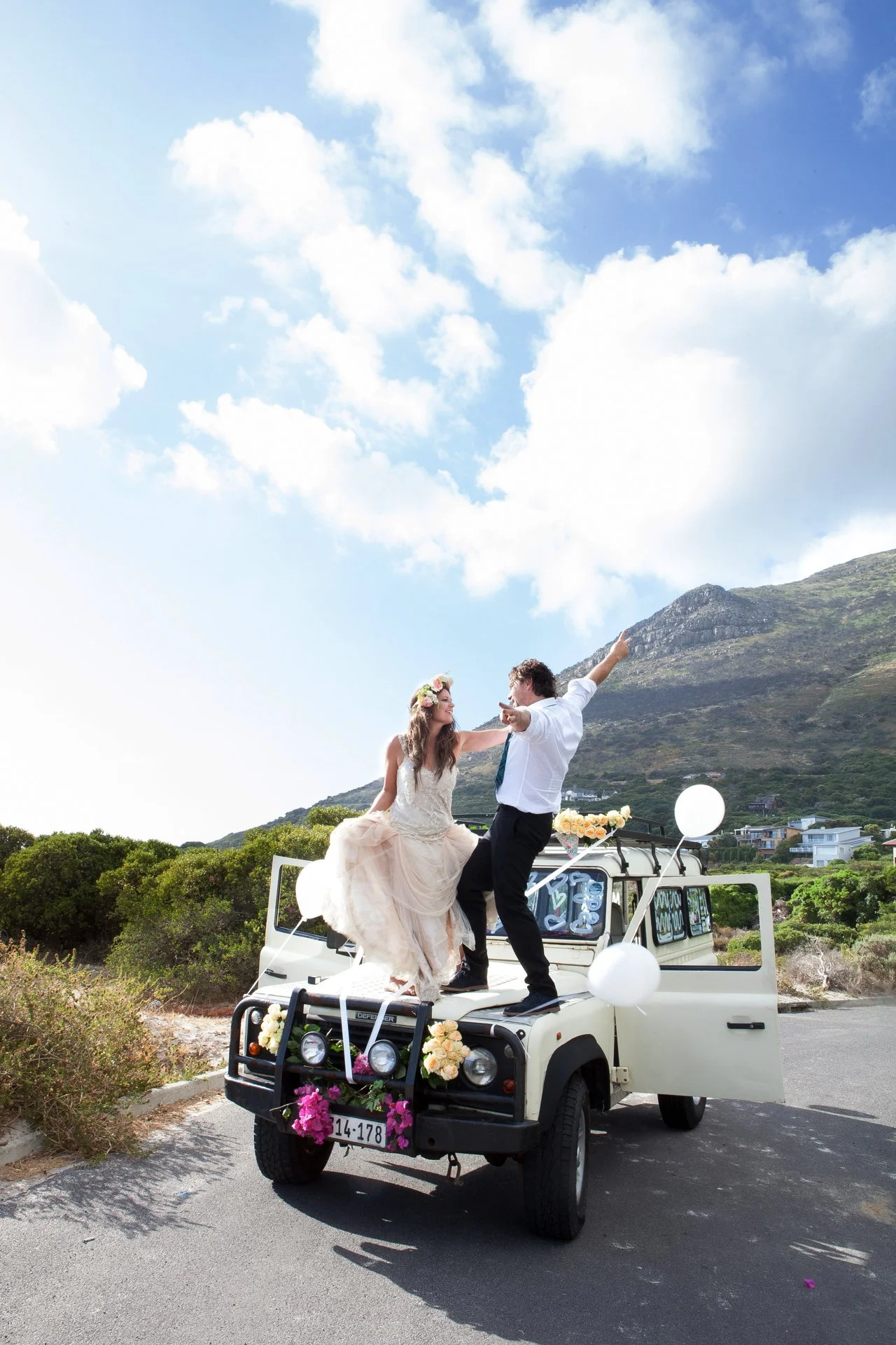bride and groom dancing on bonnet of car
