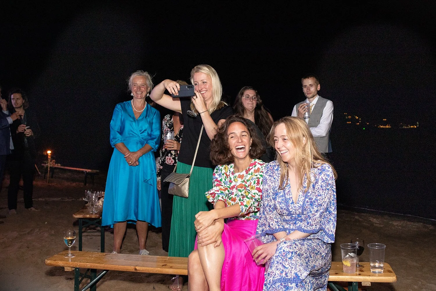 wedding party sitting on bench on the beach in devon