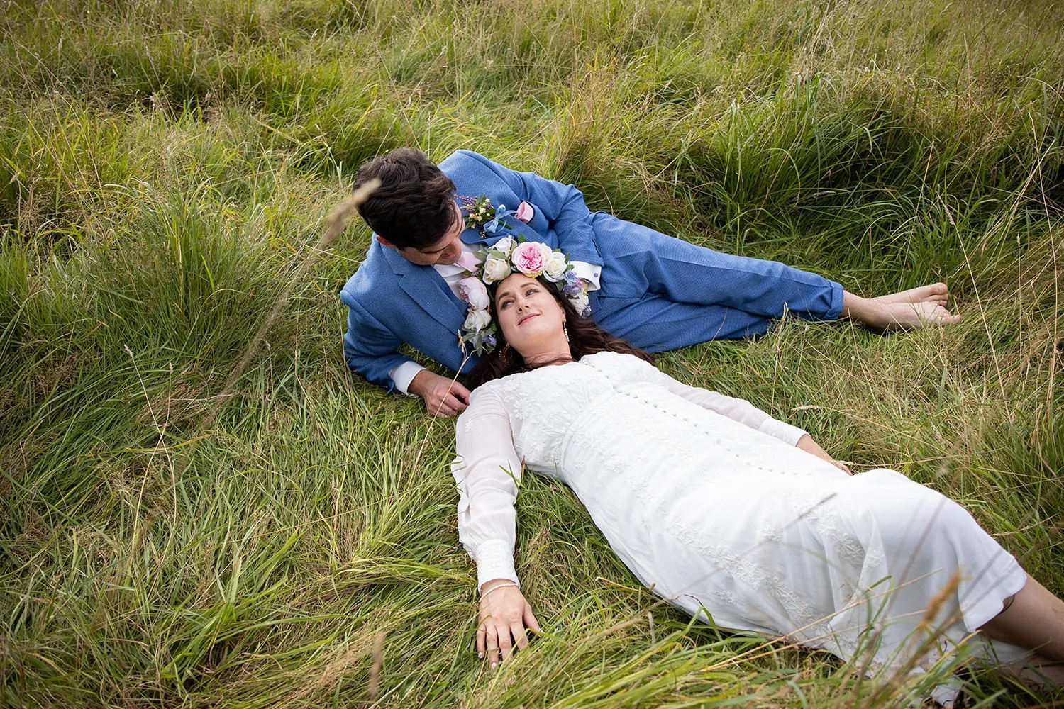 bride and groom lying in a field