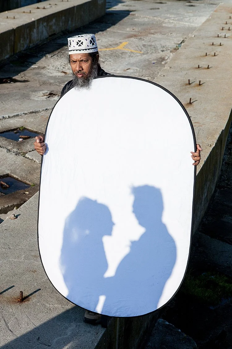 indian man holding reflector with shadows of bride and groom on it