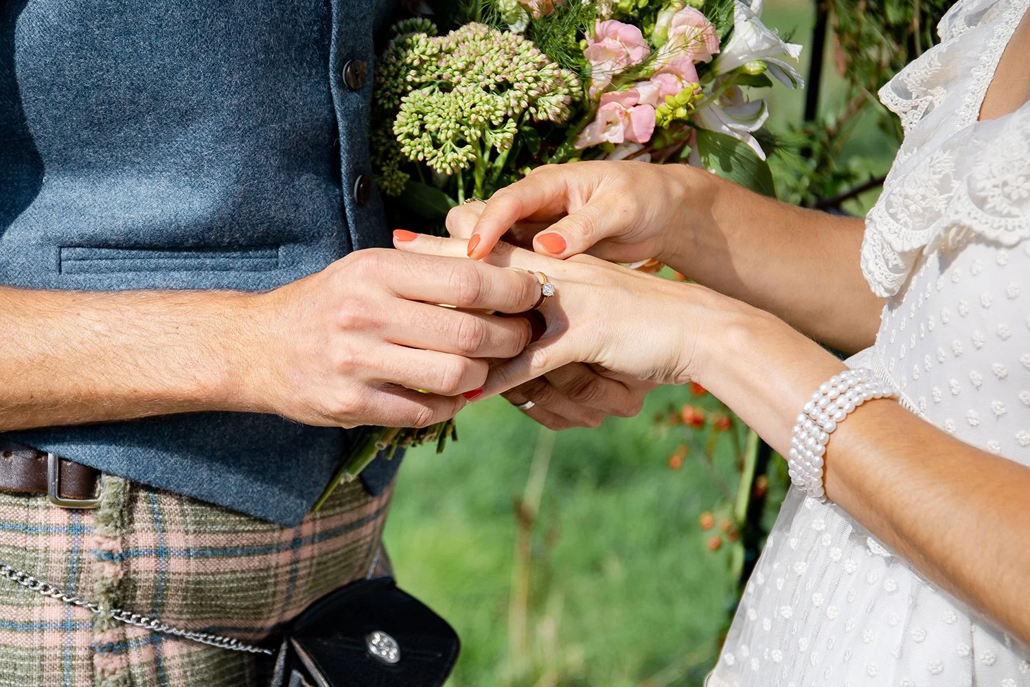 detail of groom putting ring on bride's finger