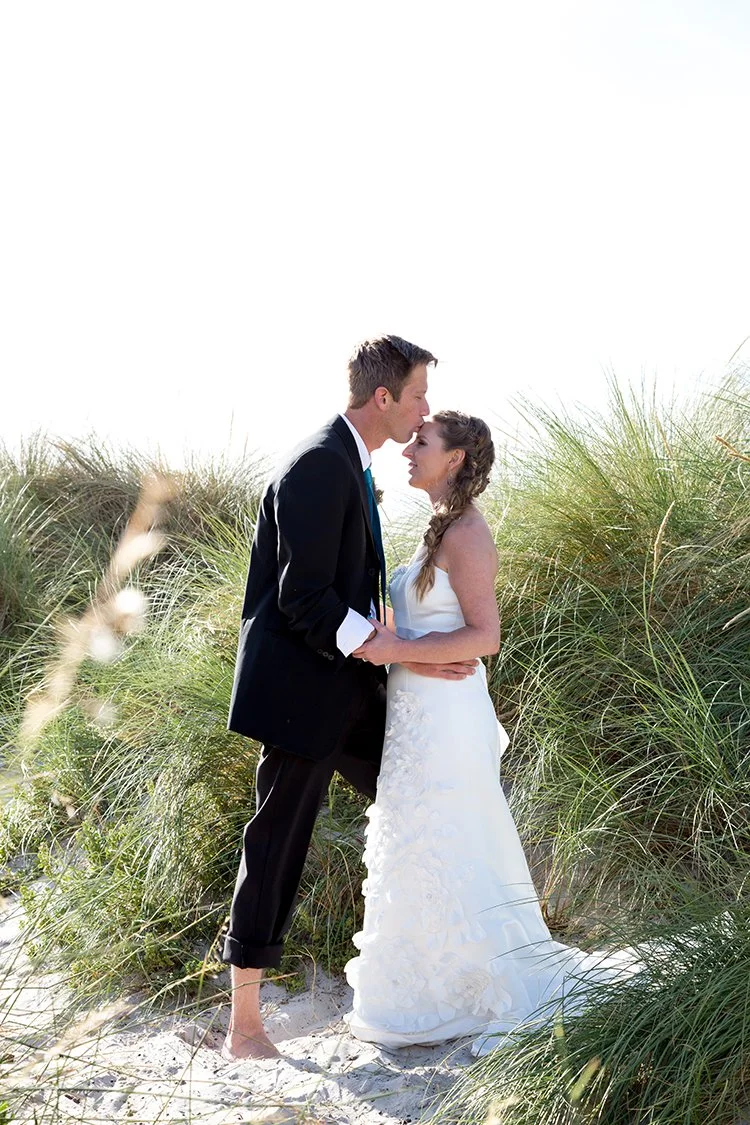 groom kissing bride in sand dune in capw town