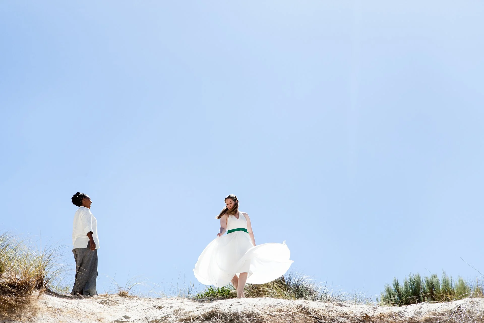 same sex couple dancing on sand dune