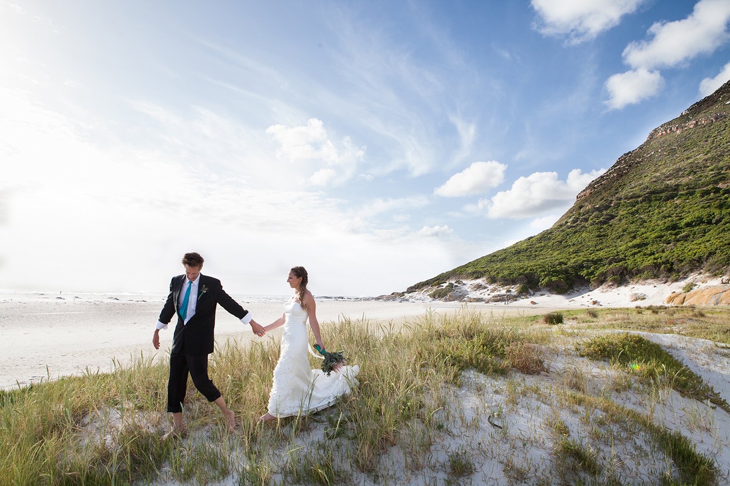 bride and groom walking on beach in cape town