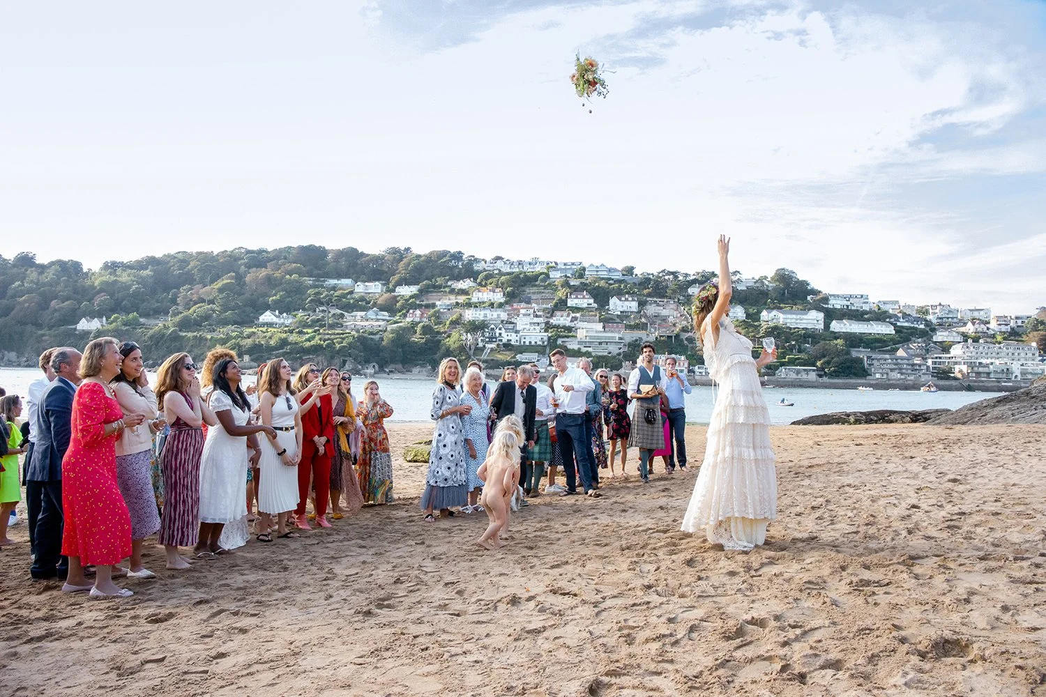 bride throwing her bouquet at beach in devon