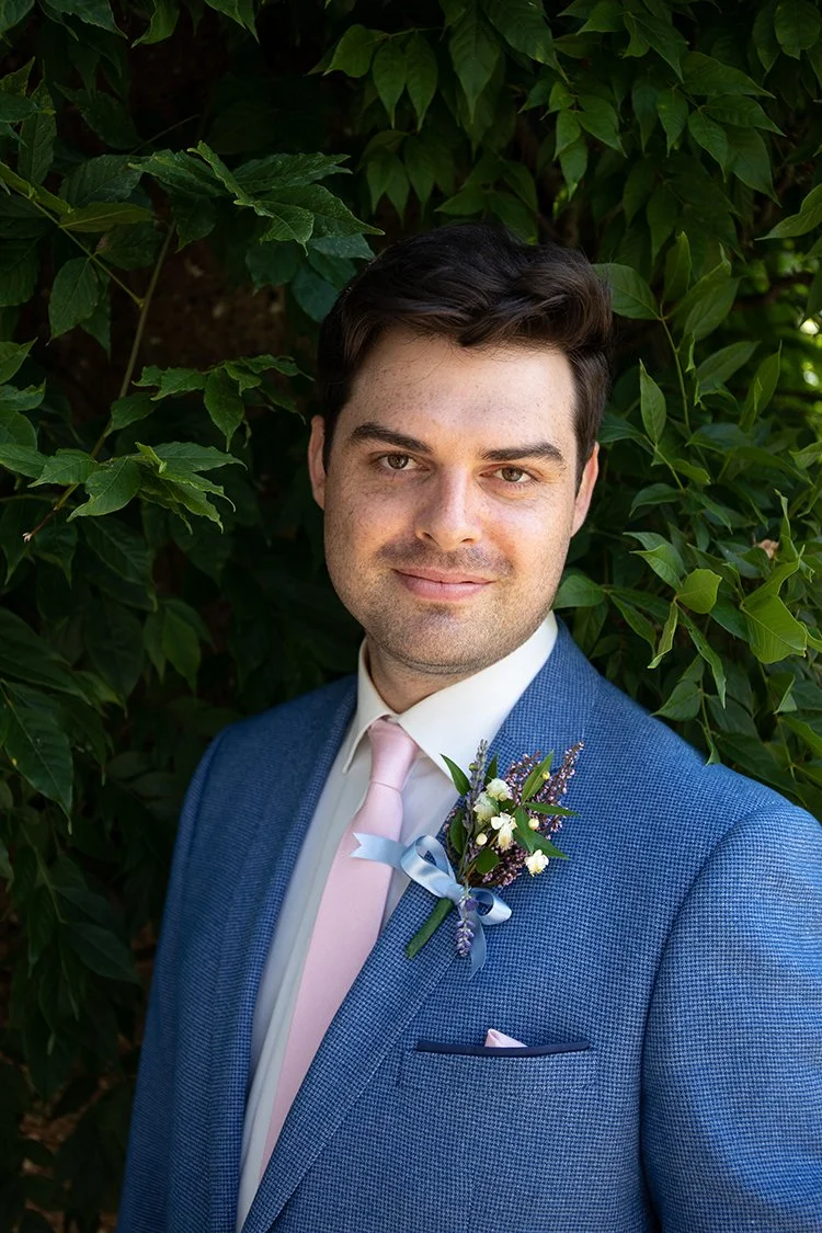 portrait of groom in front of green foliage