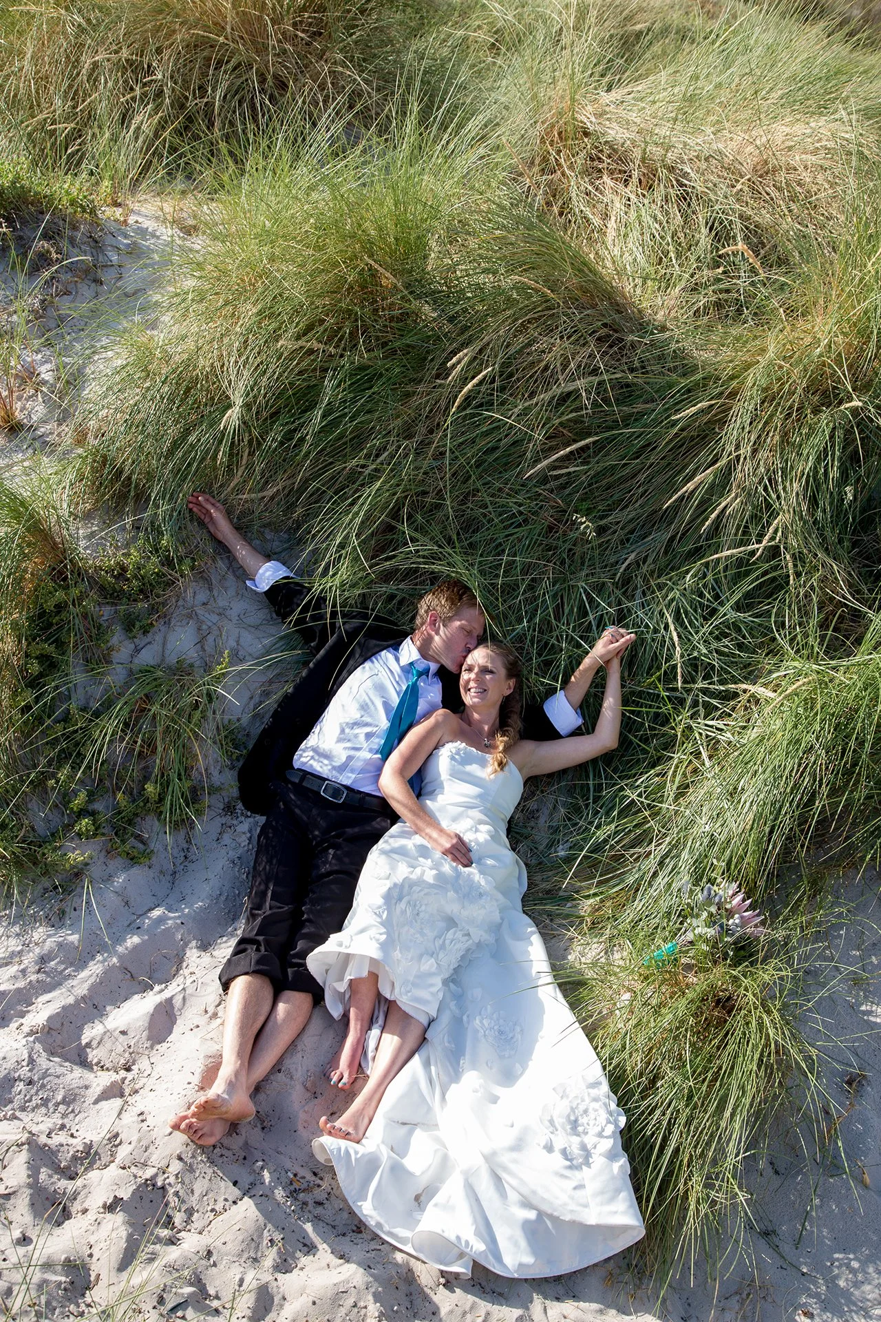bride and groom lying in dune