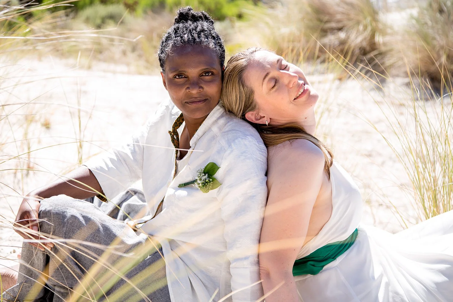 same sex couple sitting in dunes