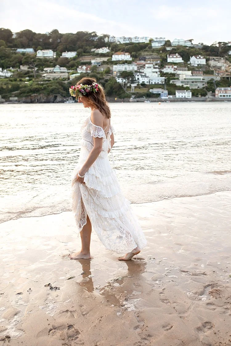 bride walking on a beach with salcombe in background