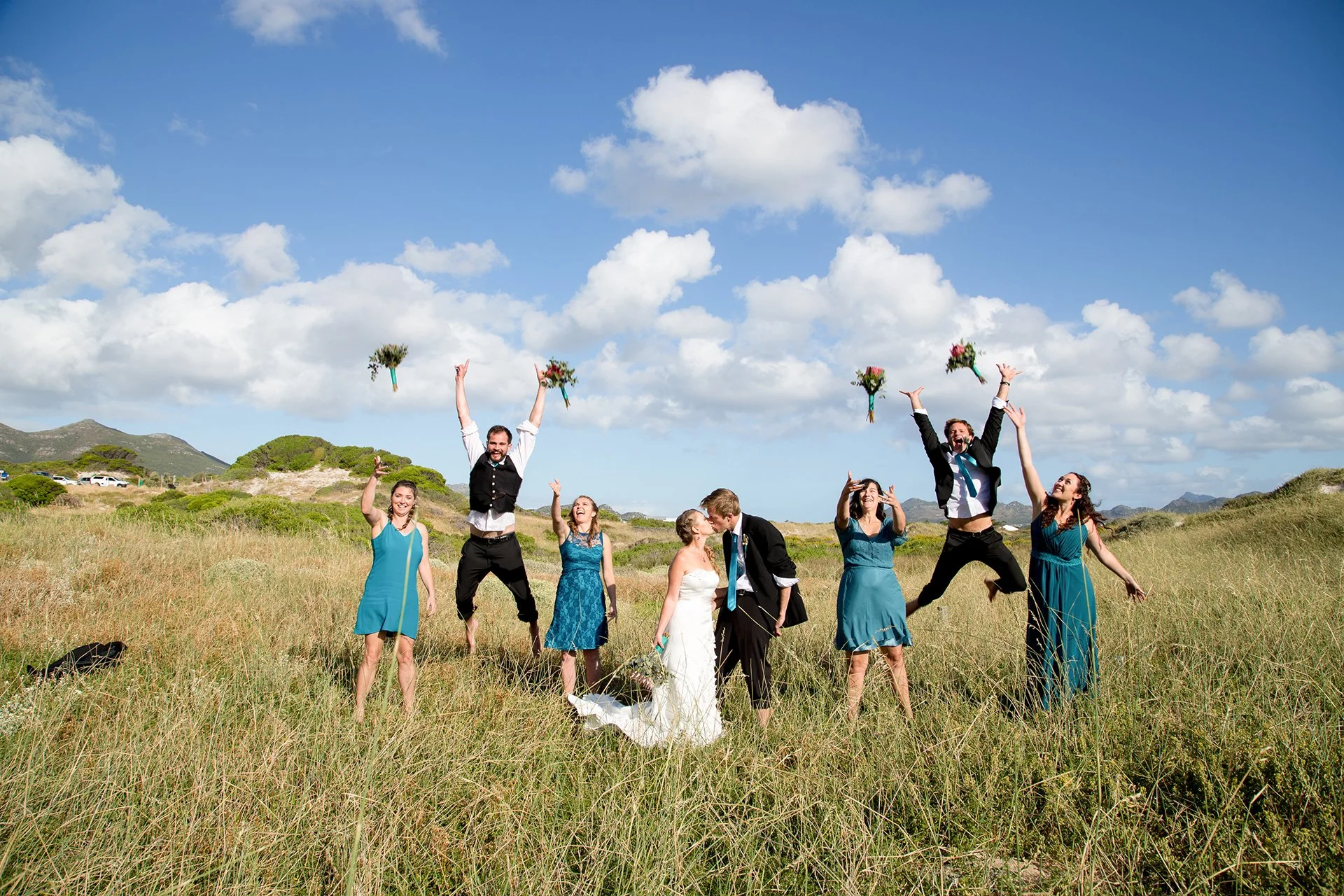 bride and groom kissing with brides maids and grooms men