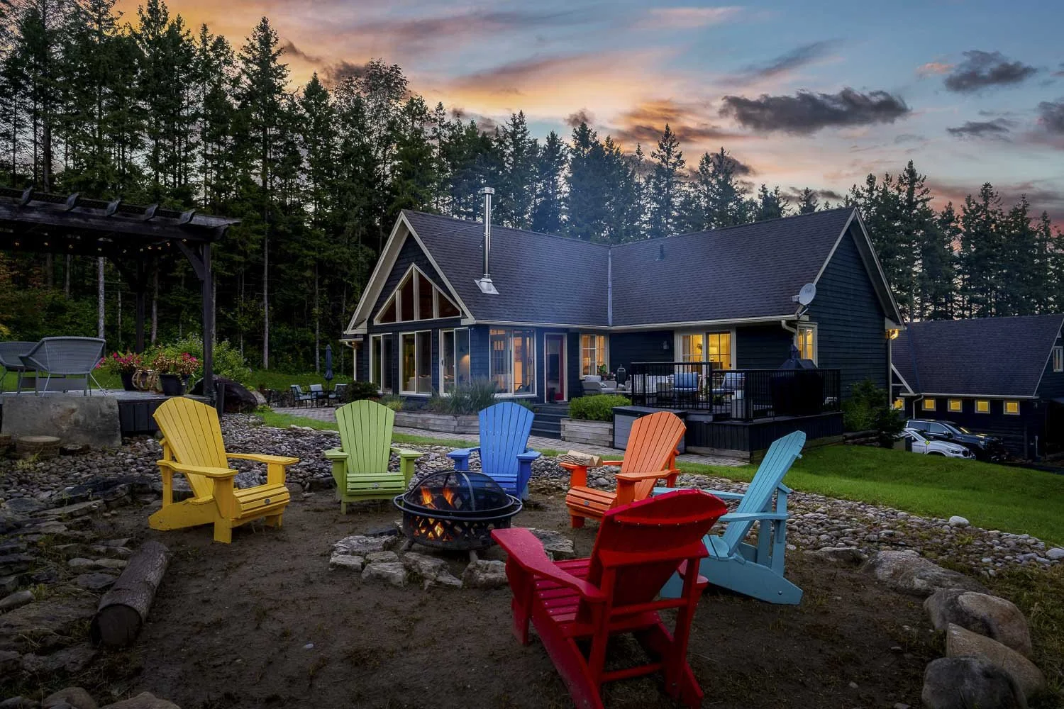 A Creemore home at night with a fire pit and colourful chairs.