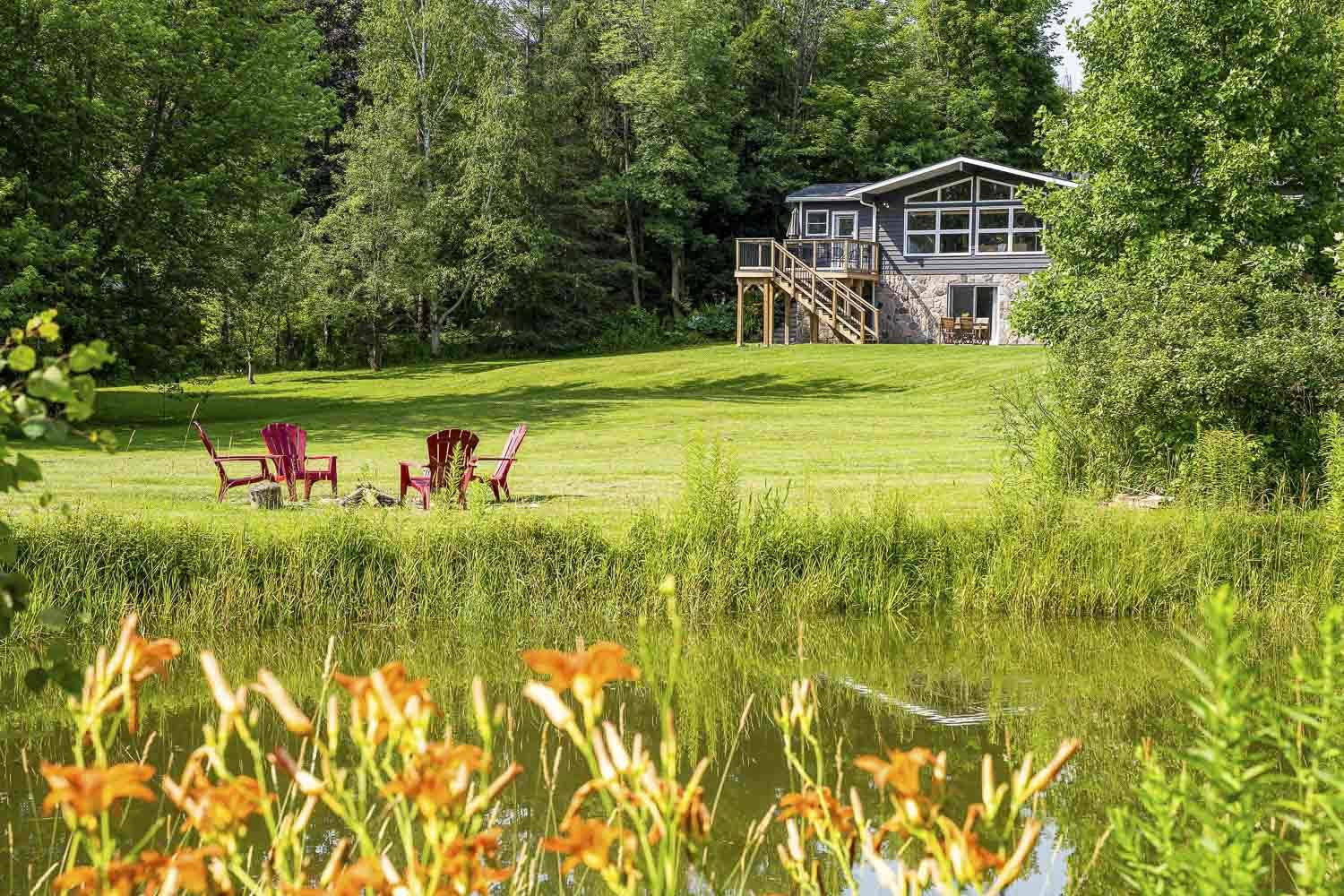 A Clearview backyard in the summertime with chairs and a pond.