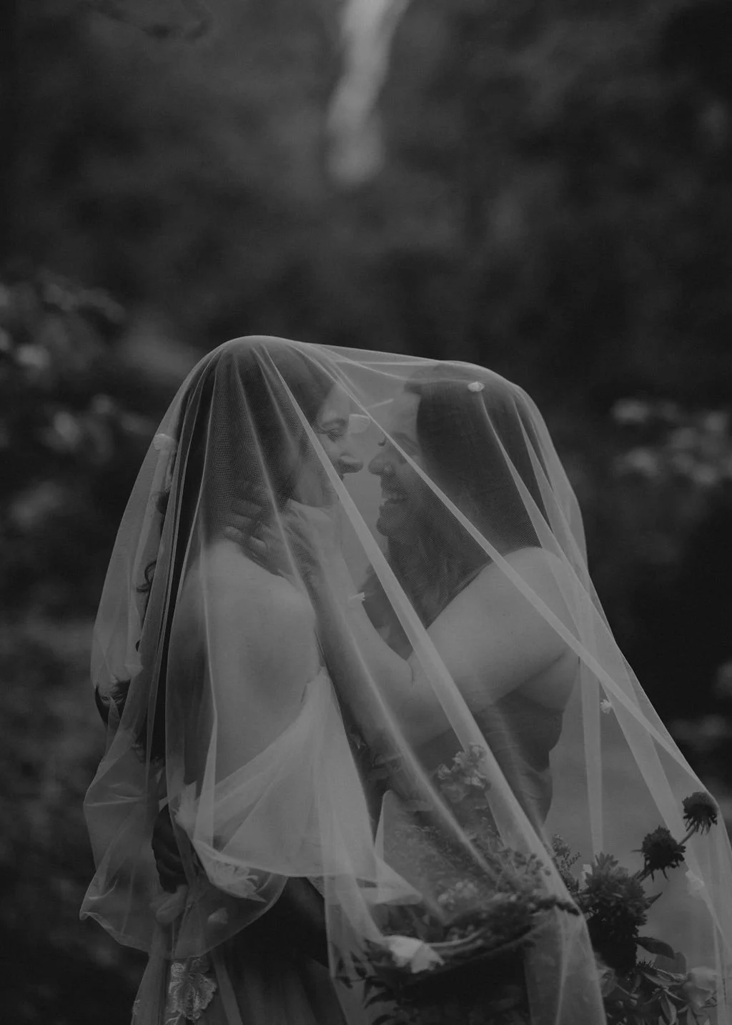    A sweet couple stands close together with a veil over their heads. One partner lovingly places her hands on the other's face. The two gaze happily into each others eyes. Everson Events plans Oregon vow renewal ceremony. #EversonEvents #VowRenewals