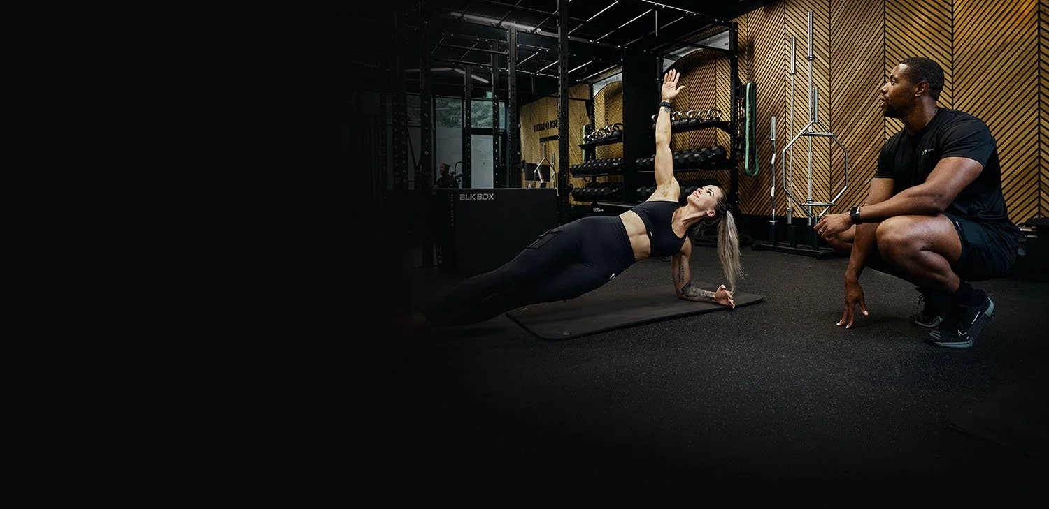 Learner practising a side plank with tutor guidance during Level 3 PT training.