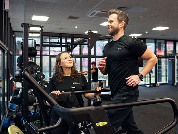 Personal trainer instructing client on gym equipment