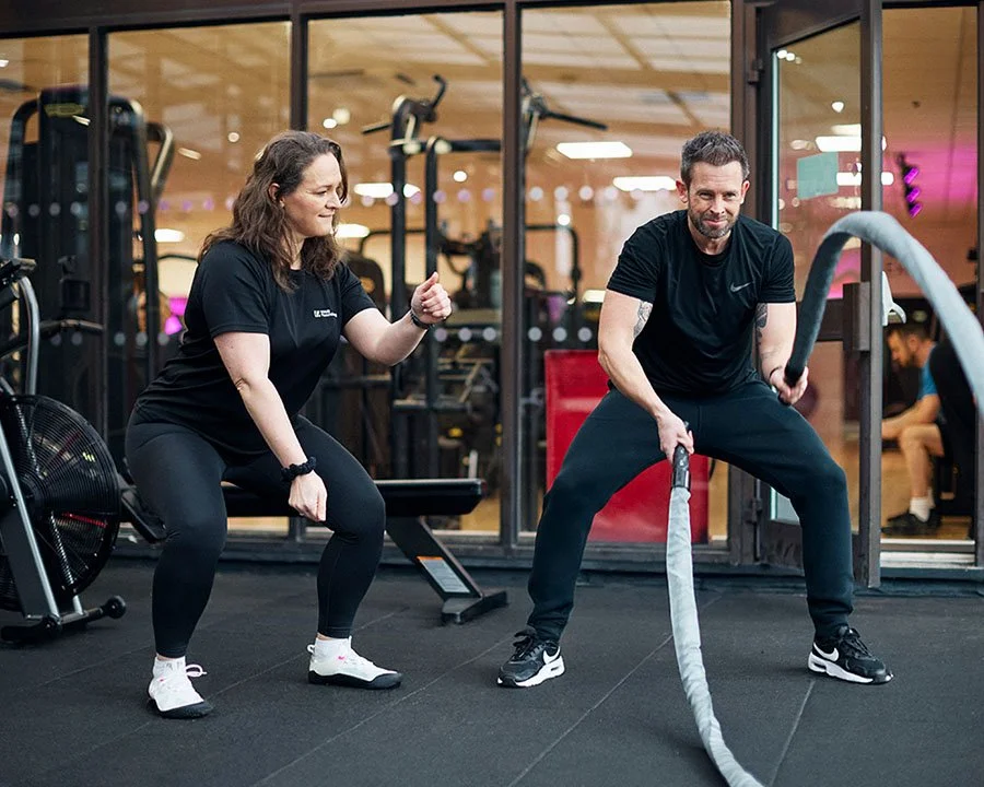 Qualified personal trainer guiding client through functional training workout