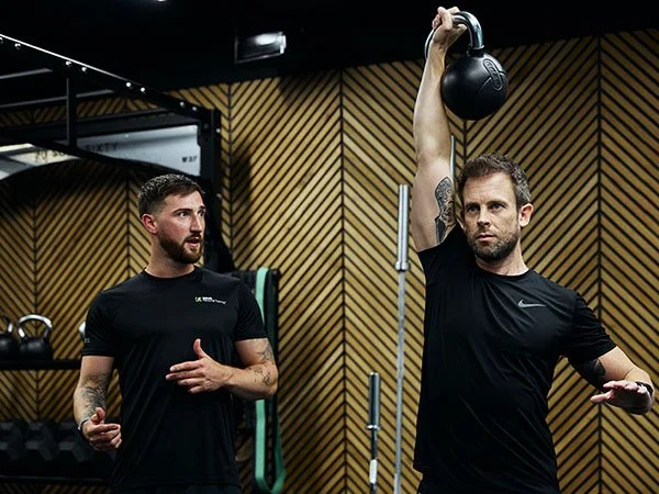 Personal trainer demonstrating exercise technique to client