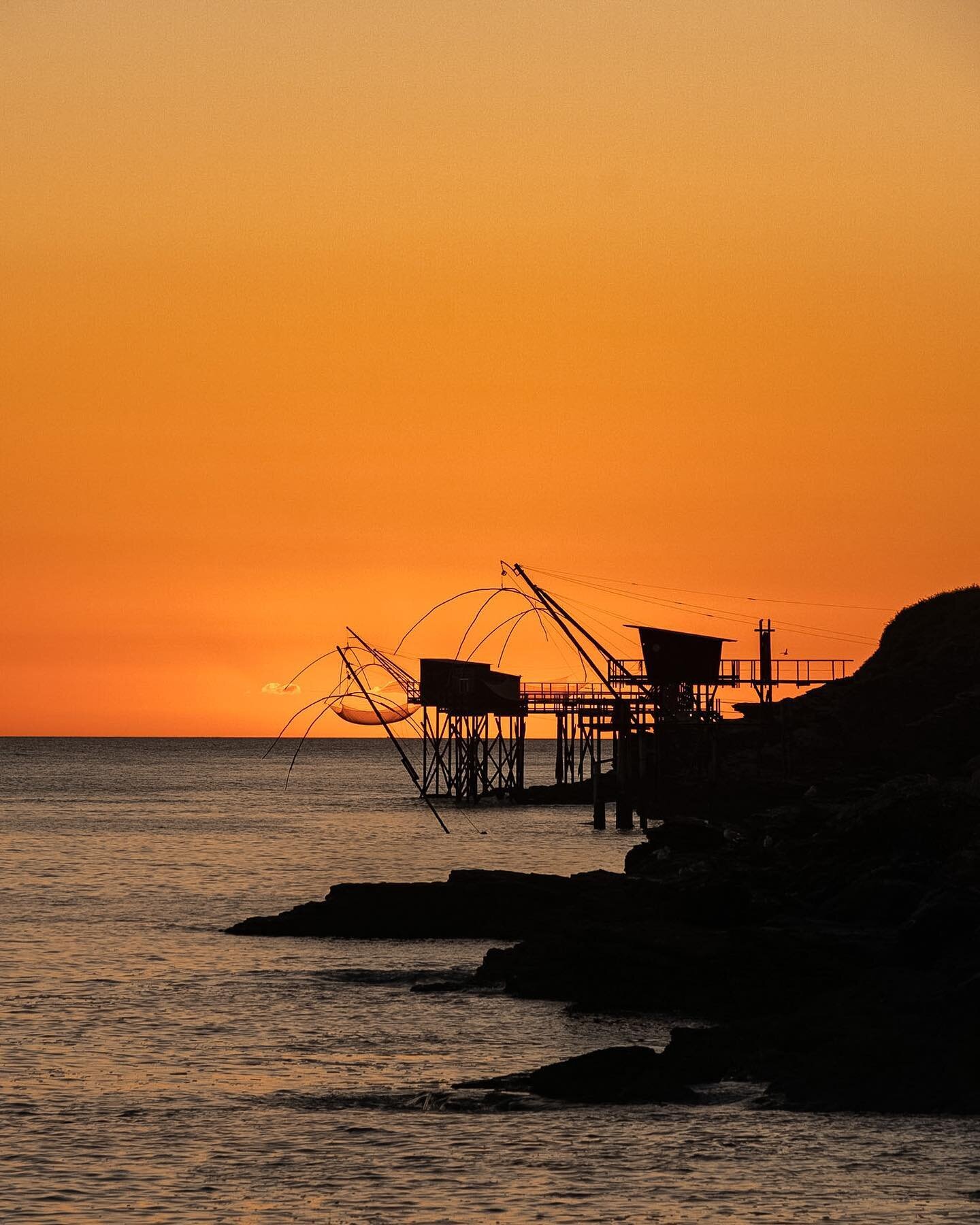 Shellfish catchers silhouetted along the french Atlantic coast! 

These strange huts dot this spectacular coastline. They reach their long arms into the sea at low tide and wait for the sand to wash in. When the time is right, they pull up the net an