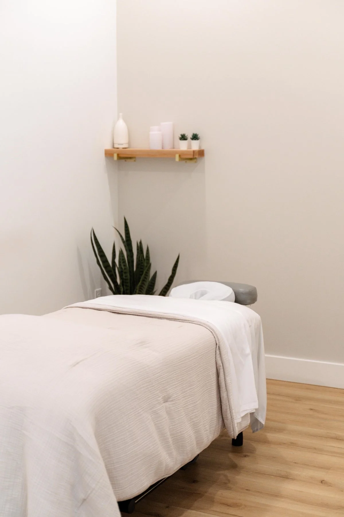 Calm massage therapy treatment room with draped table, plant and candles at The Wellness Hub in Stoney Creek, Ontario