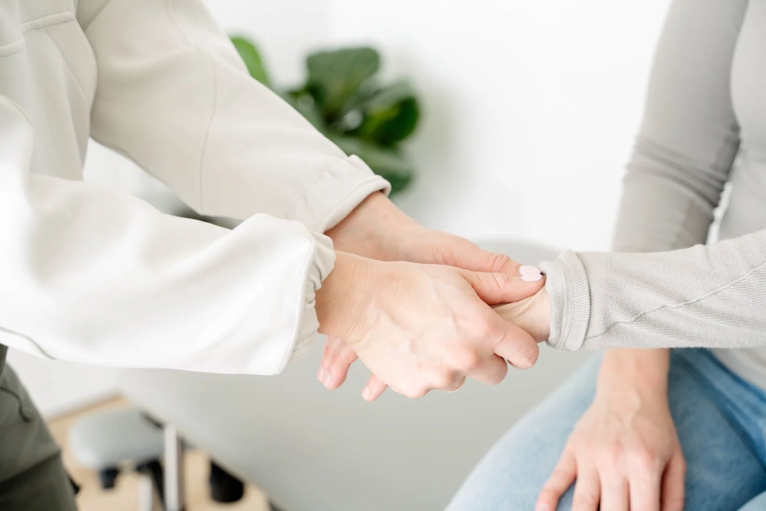 Therapist gently holding patient's hand during mommy thumb treatment at The Wellness Hub in Stoney Creek, Ontario
