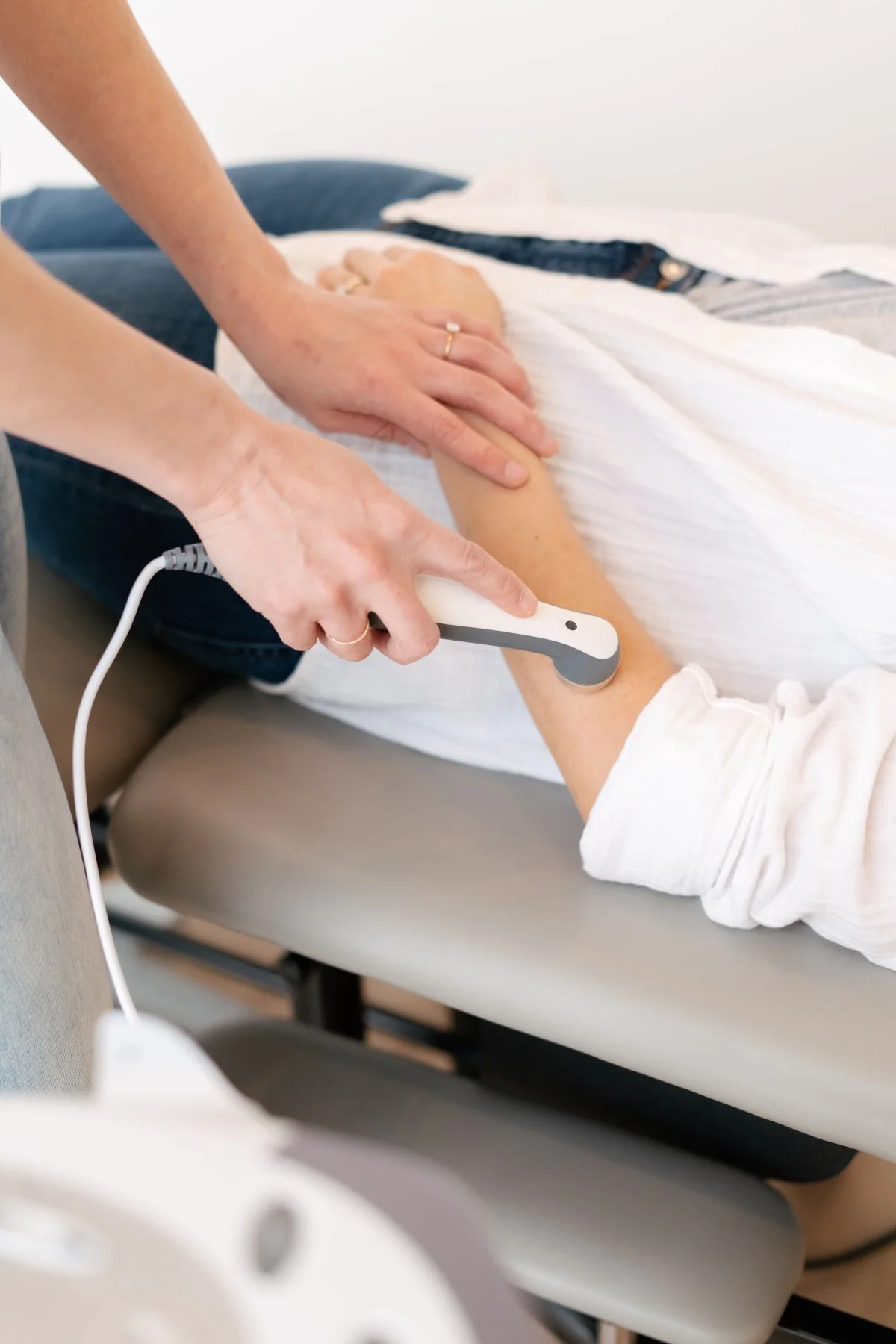 Therapist applying ultrasound therapy to a patient's forearm at The Wellness Hub in Stoney Creek, Ontario