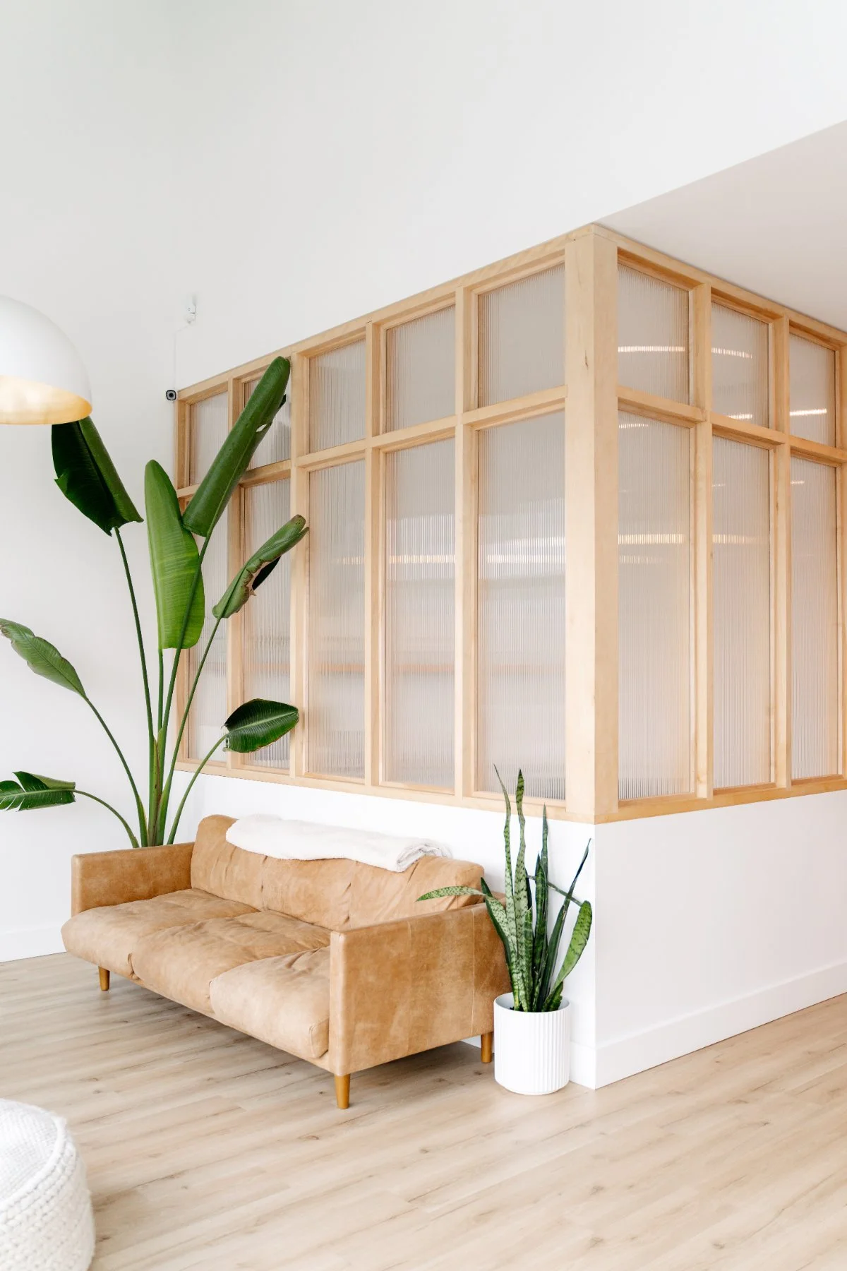 Bright reception waiting area with tan leather sofa and greenery at The Wellness Hub in Stoney Creek, Ontario