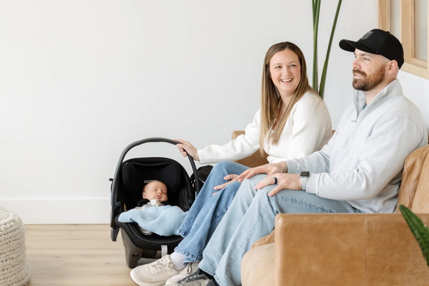 New parents sitting with their newborn in a car seat, postpartum care at The Wellness Hub in Stoney Creek, Ontario