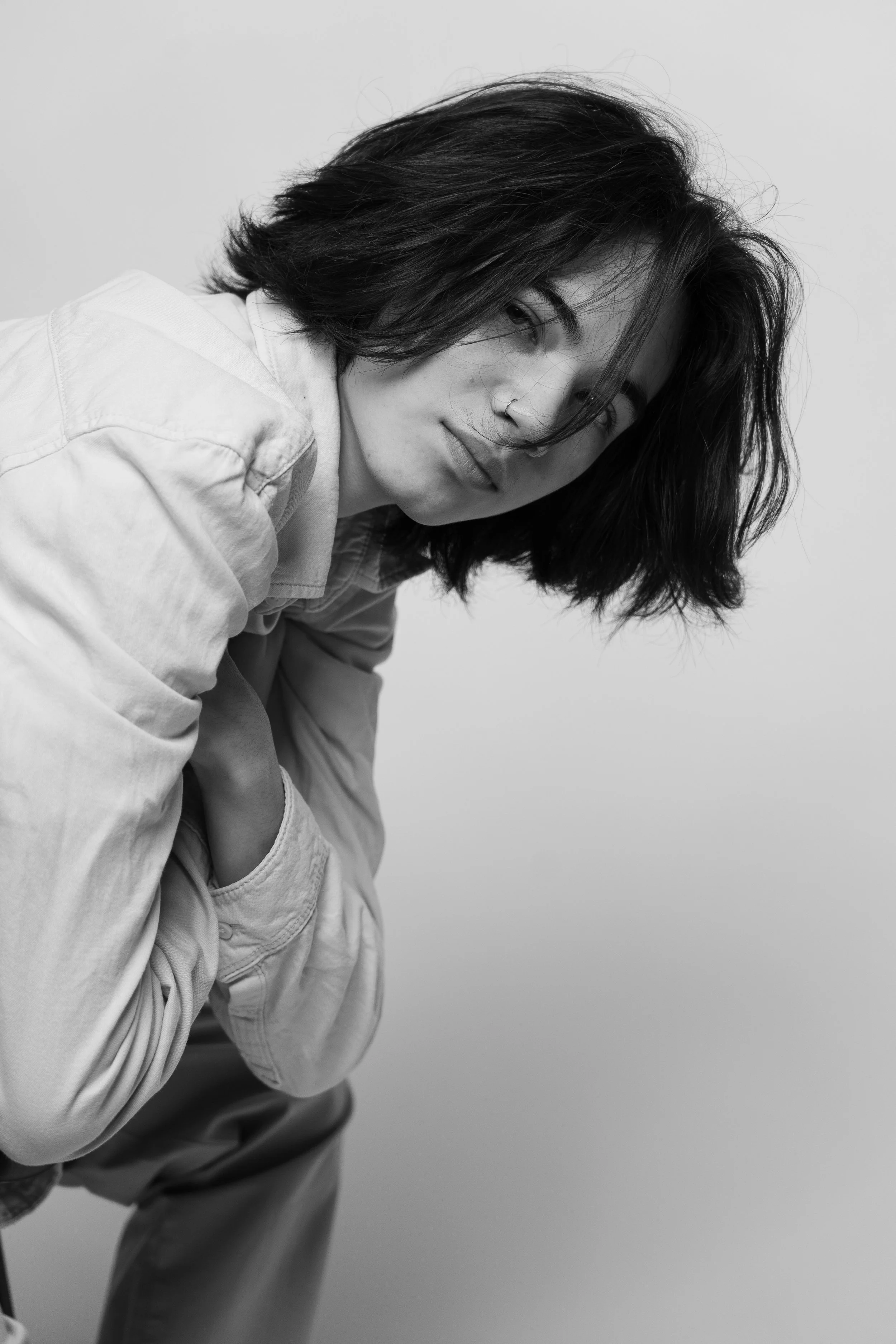 Black and white portrait of a woman with shoulder-length dark hair, wearing a light-colored shirt, looking at the camera with a neutral expression, against a plain background.