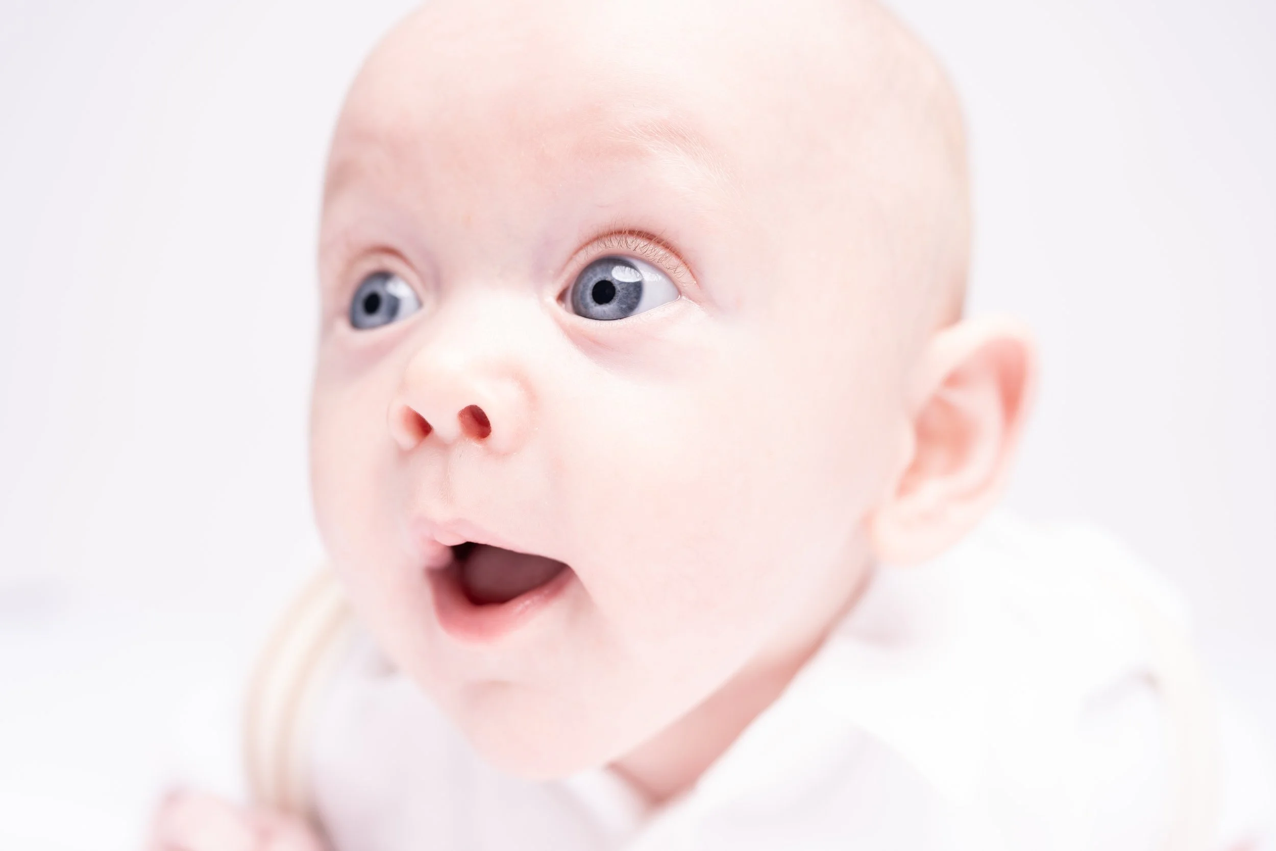 Close-up of a baby with blue eyes and a surprised or curious expression