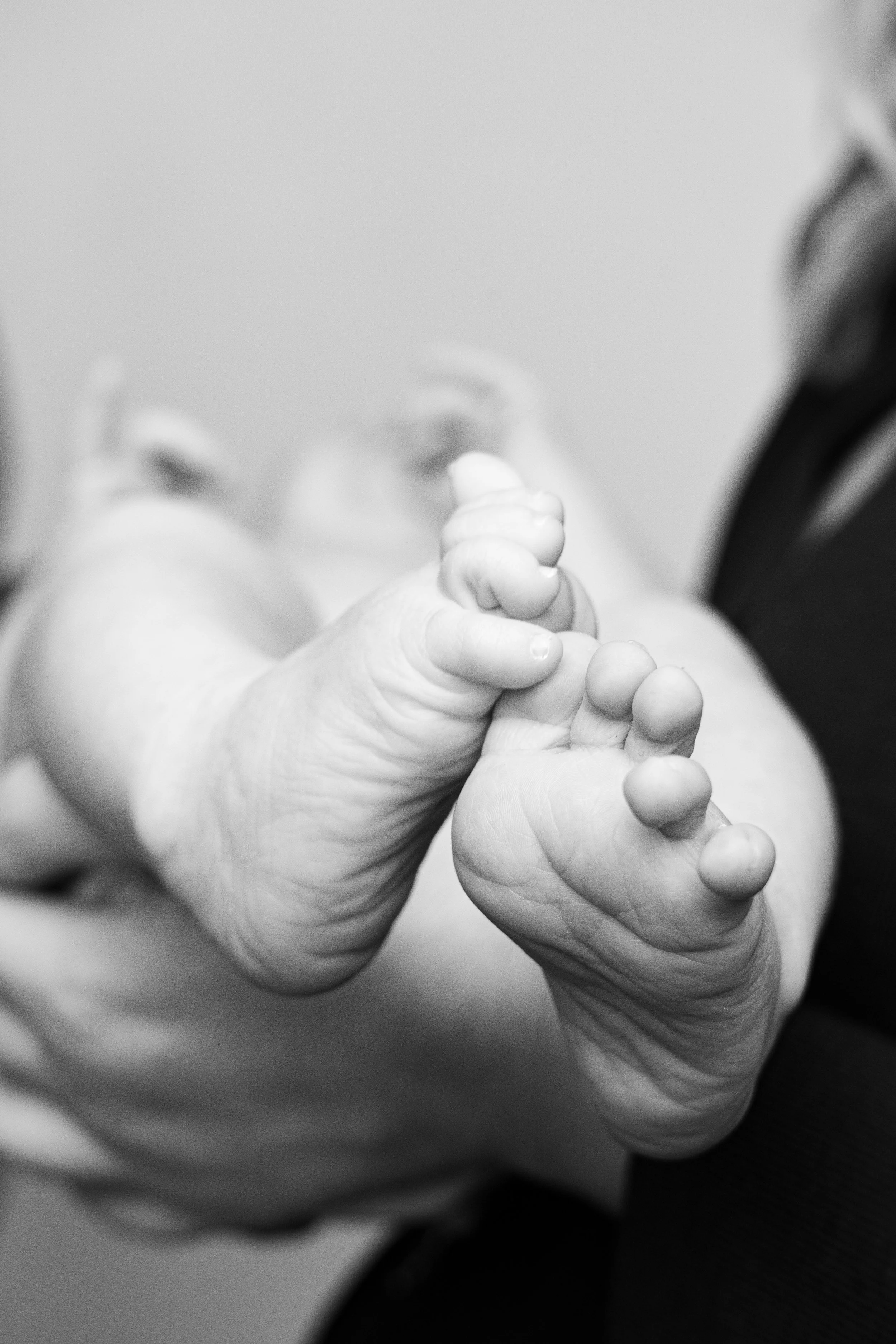 Close-up of a baby's hand gripping an adult's finger.