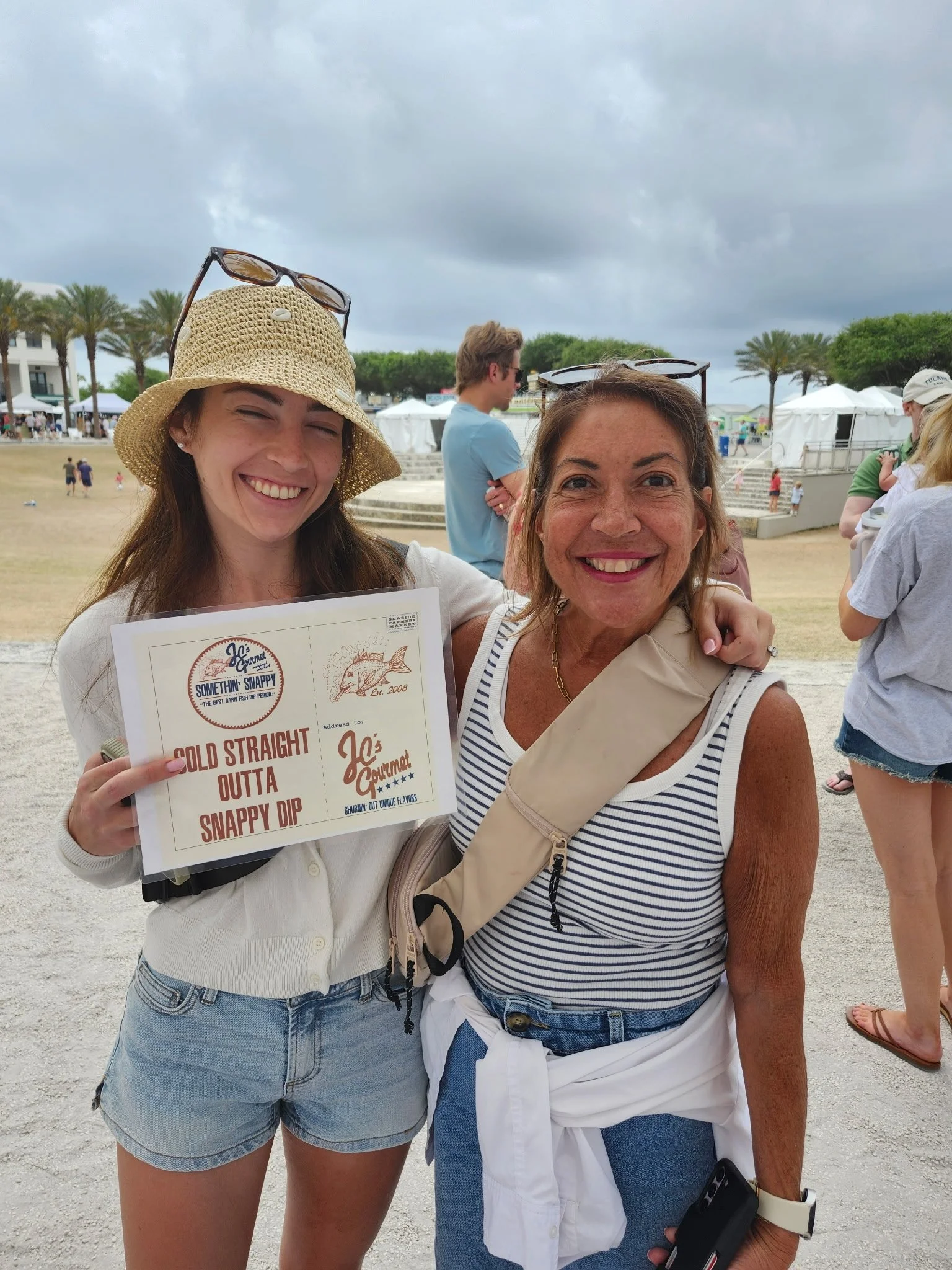Photograph of Emily (L) and Lisa (R) holding a "Sold Straight Outta Snappy Dip" sign at the Seaside Farmers Market in Florida