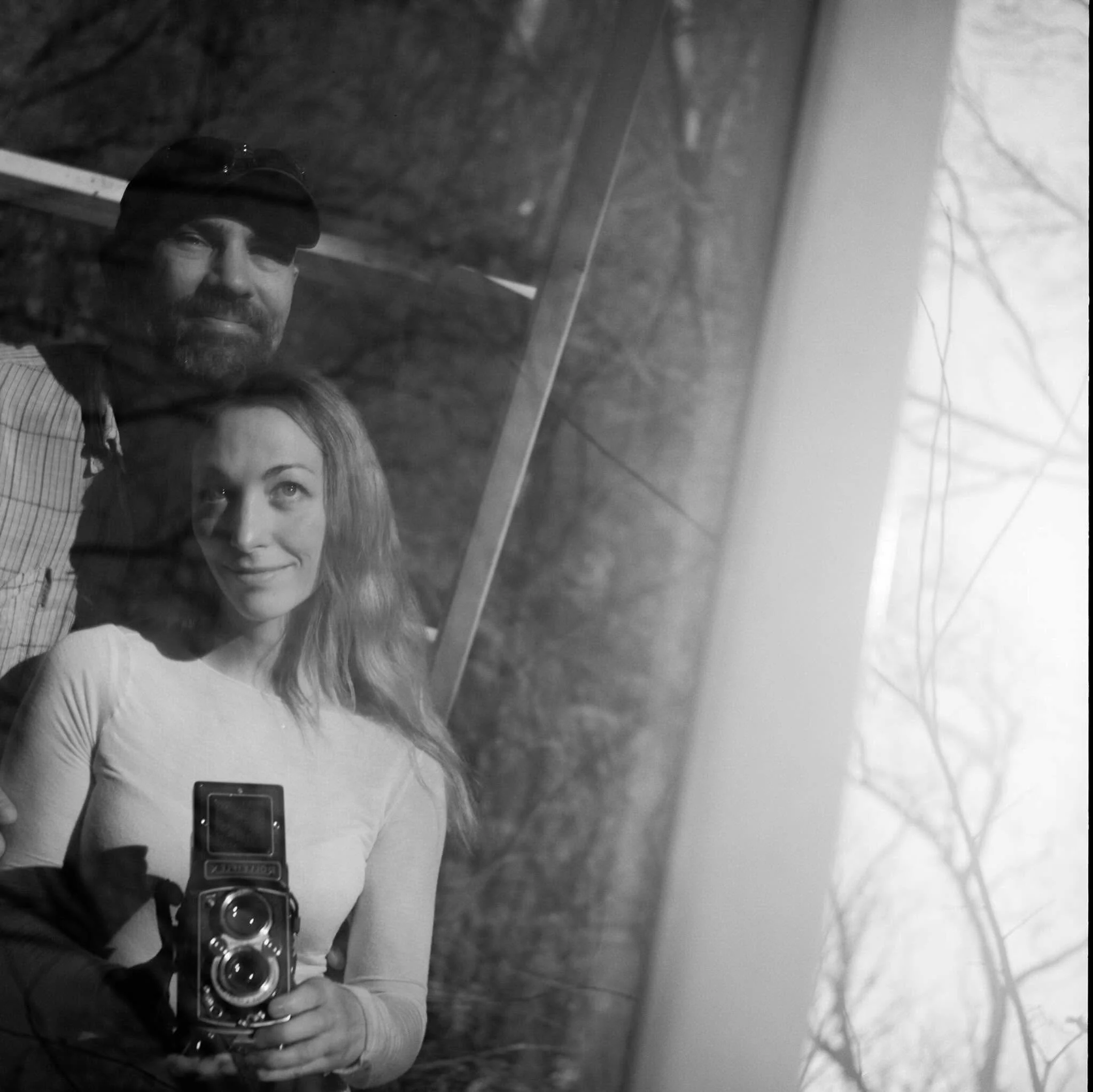 Danielle Dolan takes a black and white mirror selfie on film using a reflective surface outside on a bridge with her Rolleiflex medium format film camera.