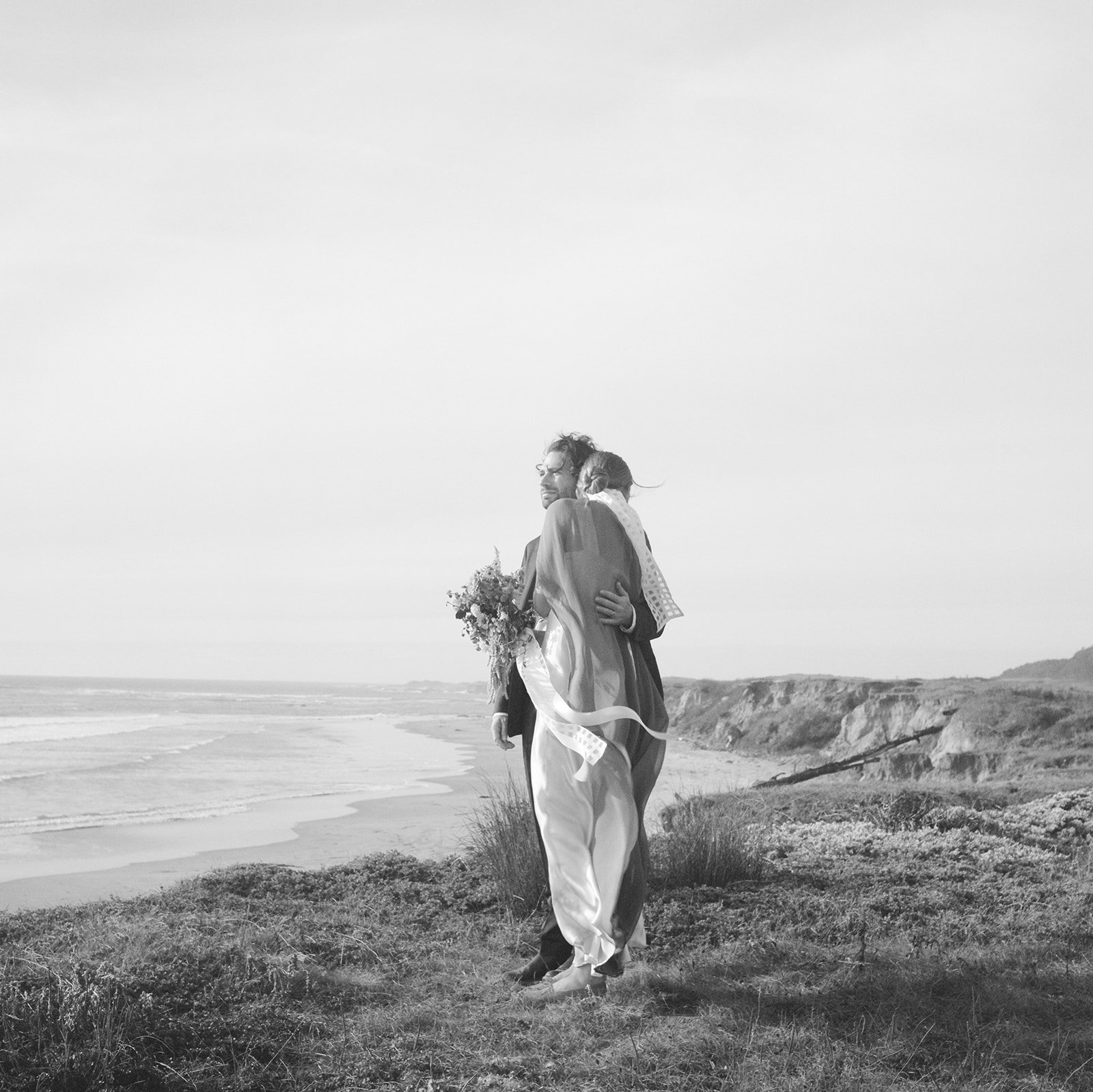 A black-and-white photo of a man and woman sitting in a living room, smiling and engaging in conversation.