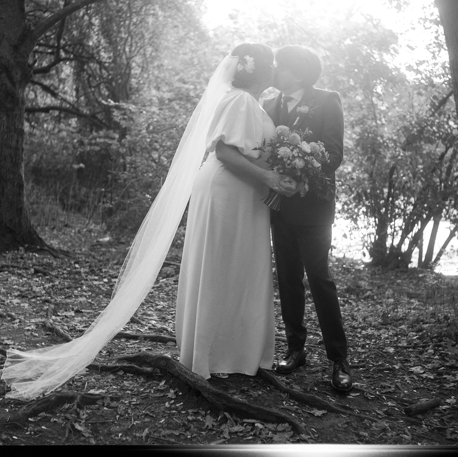 A bride and groom sharing their first dance outdoors at sunset during a wedding reception, with guests watching in the background.