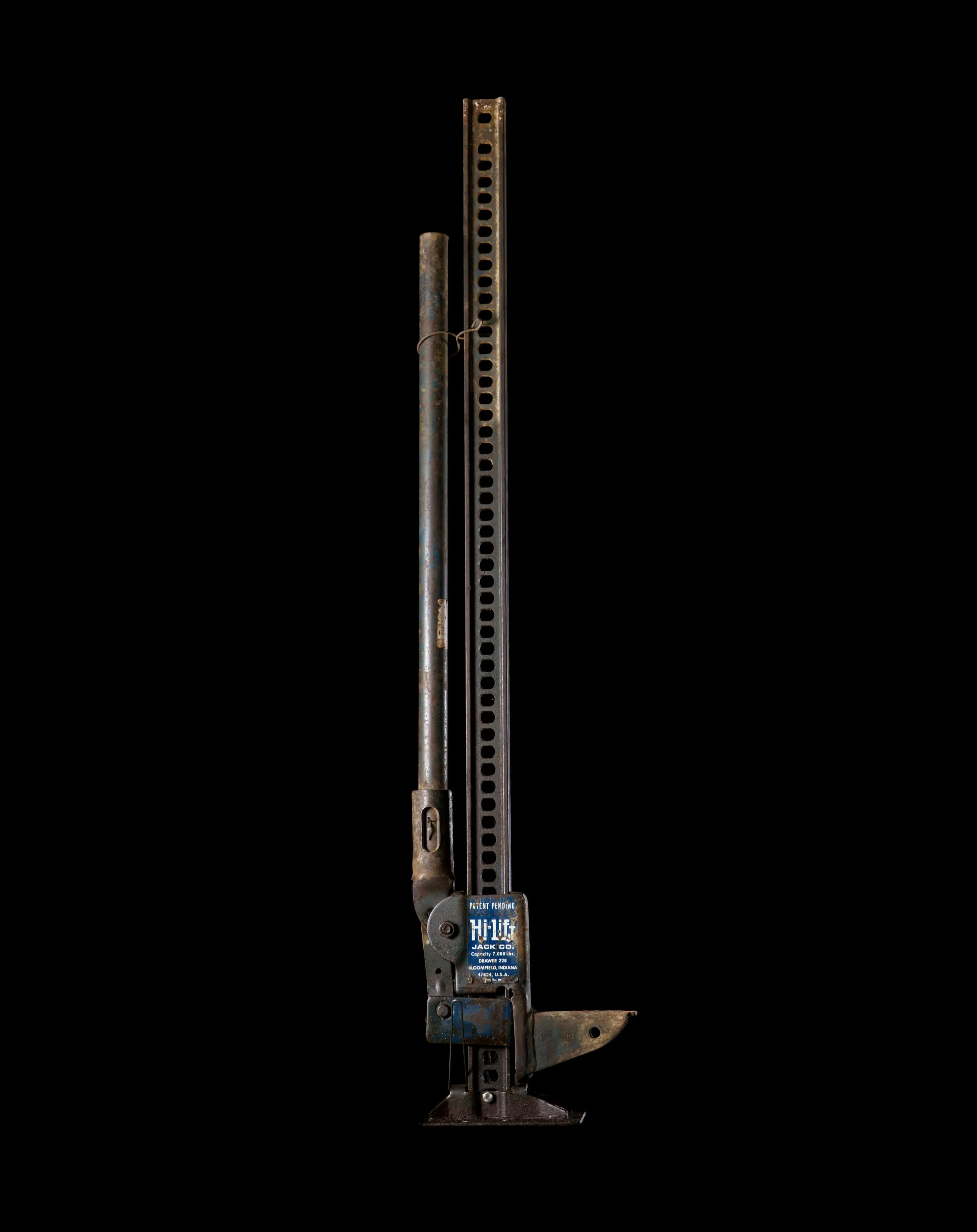 Portrait of a Hi Lift Jack against a black background, found in a barn