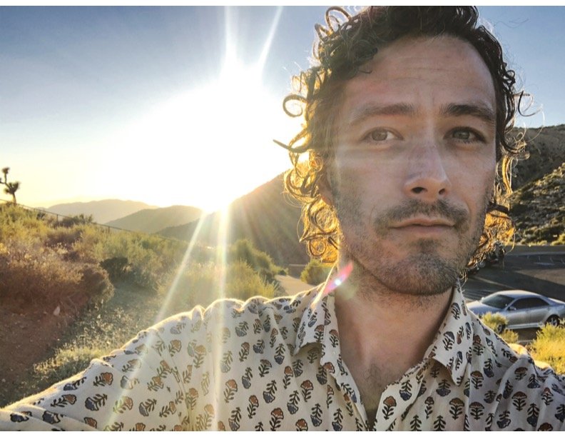Engineer Peter Munters in a desert landscape during sunset, with mountains in the background and a car parked on the side of the road.