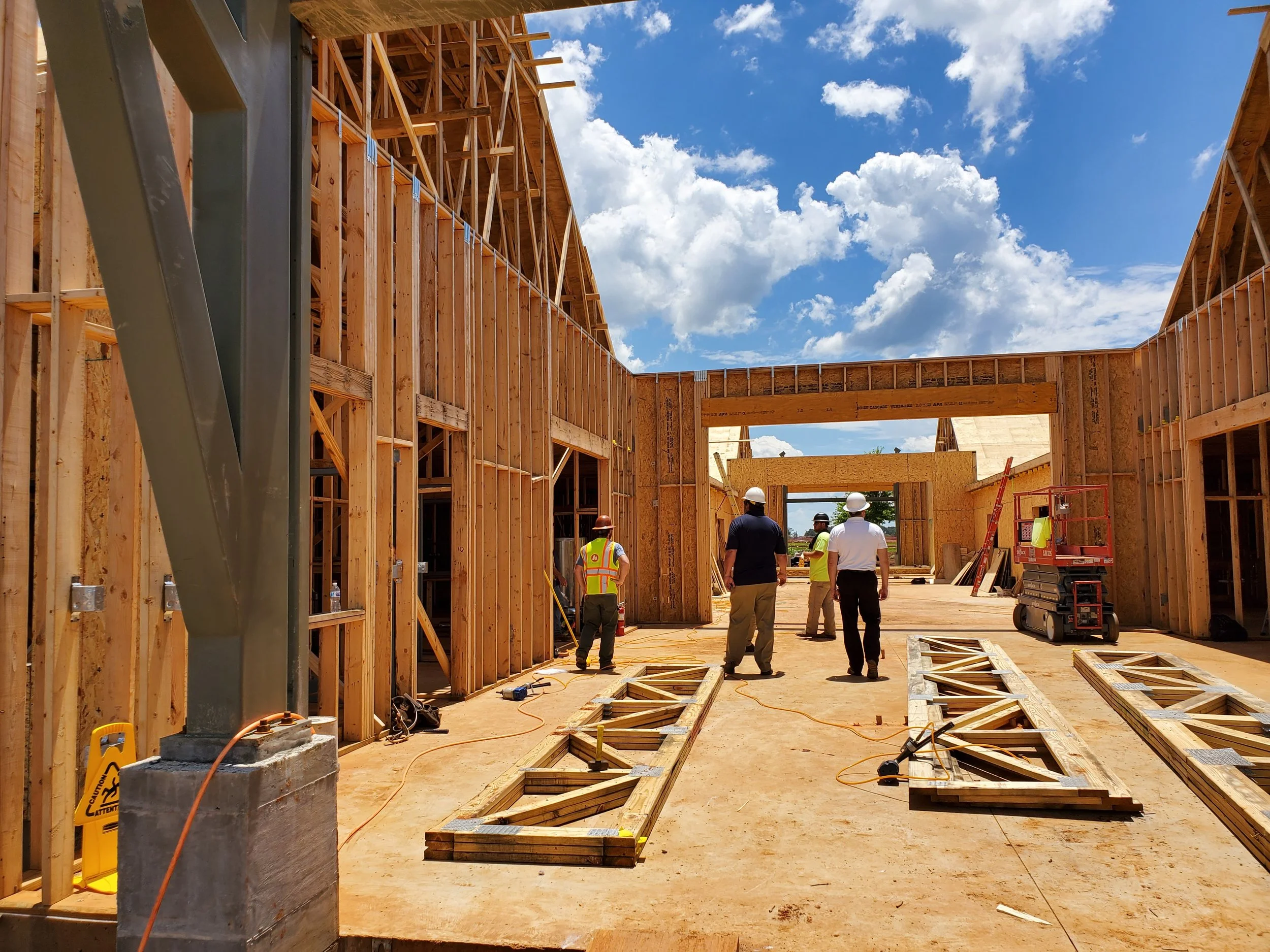 Construction workers and architects inspecting a wooden framework of a building on a sunny day.